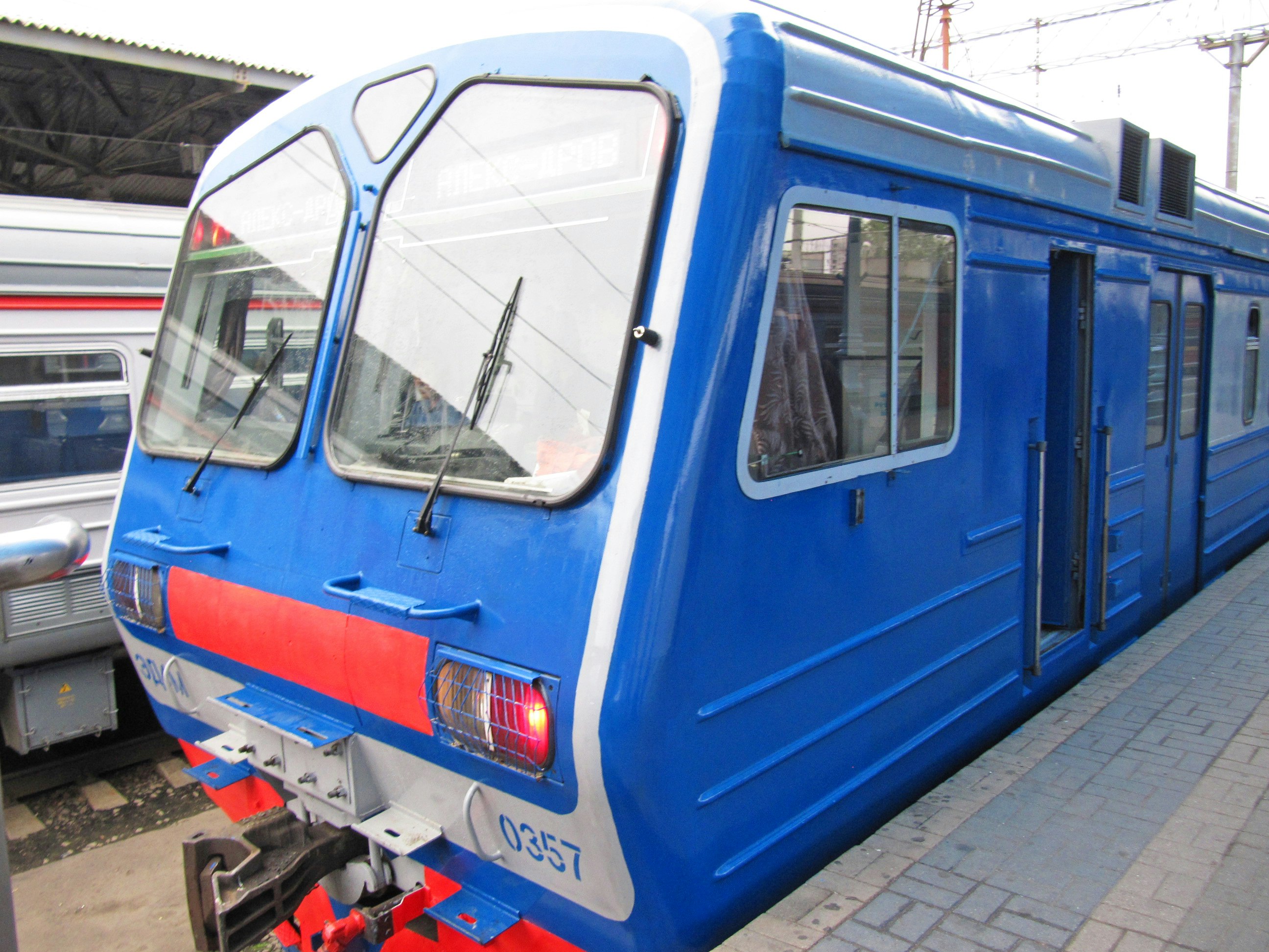 หัวรถไฟสีฟ้าและสีขาวจอดอยู่บนชานชาลาสถานี