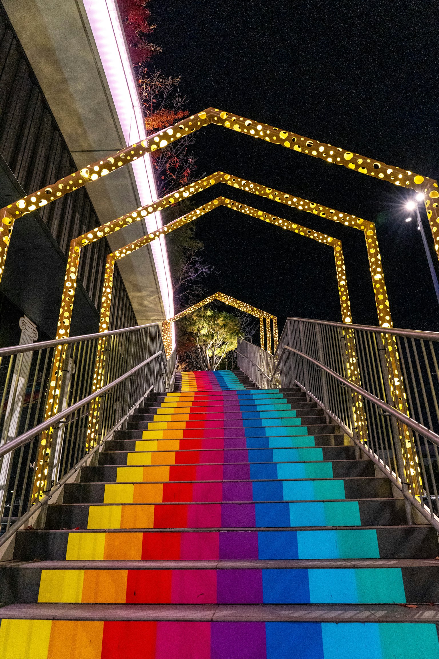 บันไดสีสันสดใสที่มีขั้นบันไดสีรุ้งสว่างไสวด้วยไฟตกแต่งในเวลากลางคืน