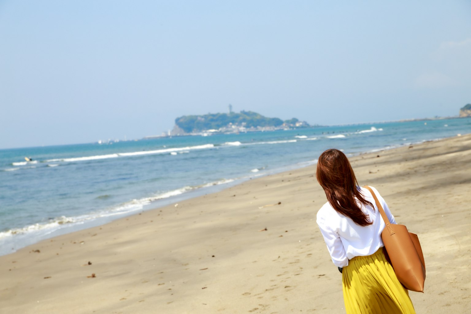 A woman walking on the beach looking at the sea