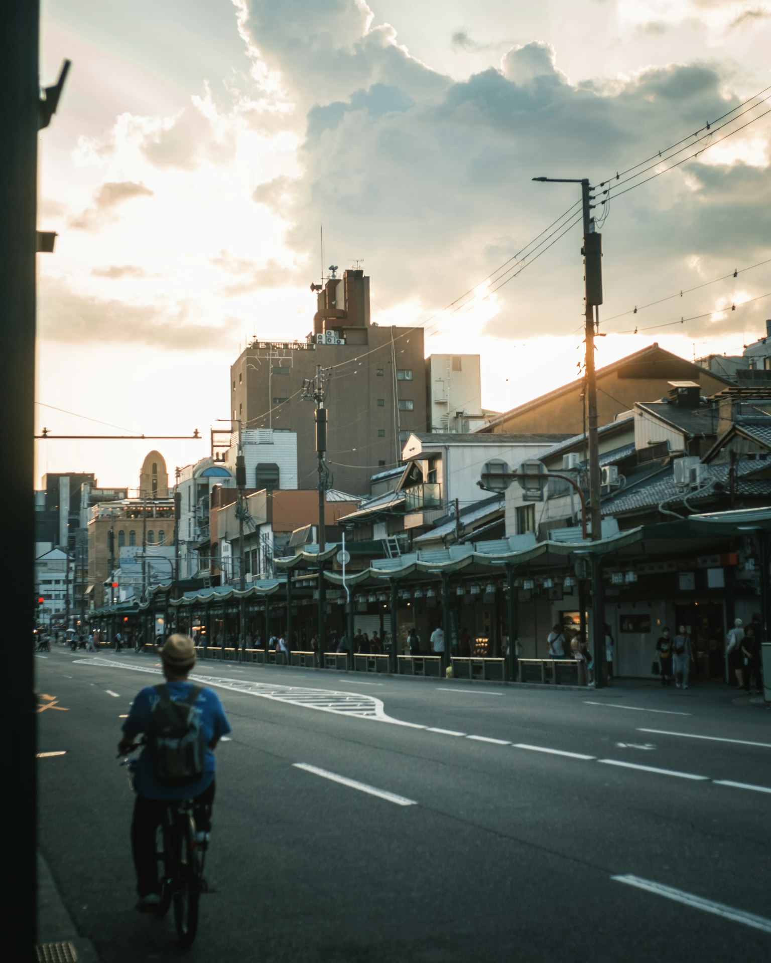 夕暮れ時の街並みを自転車で走る人物と静かな通り