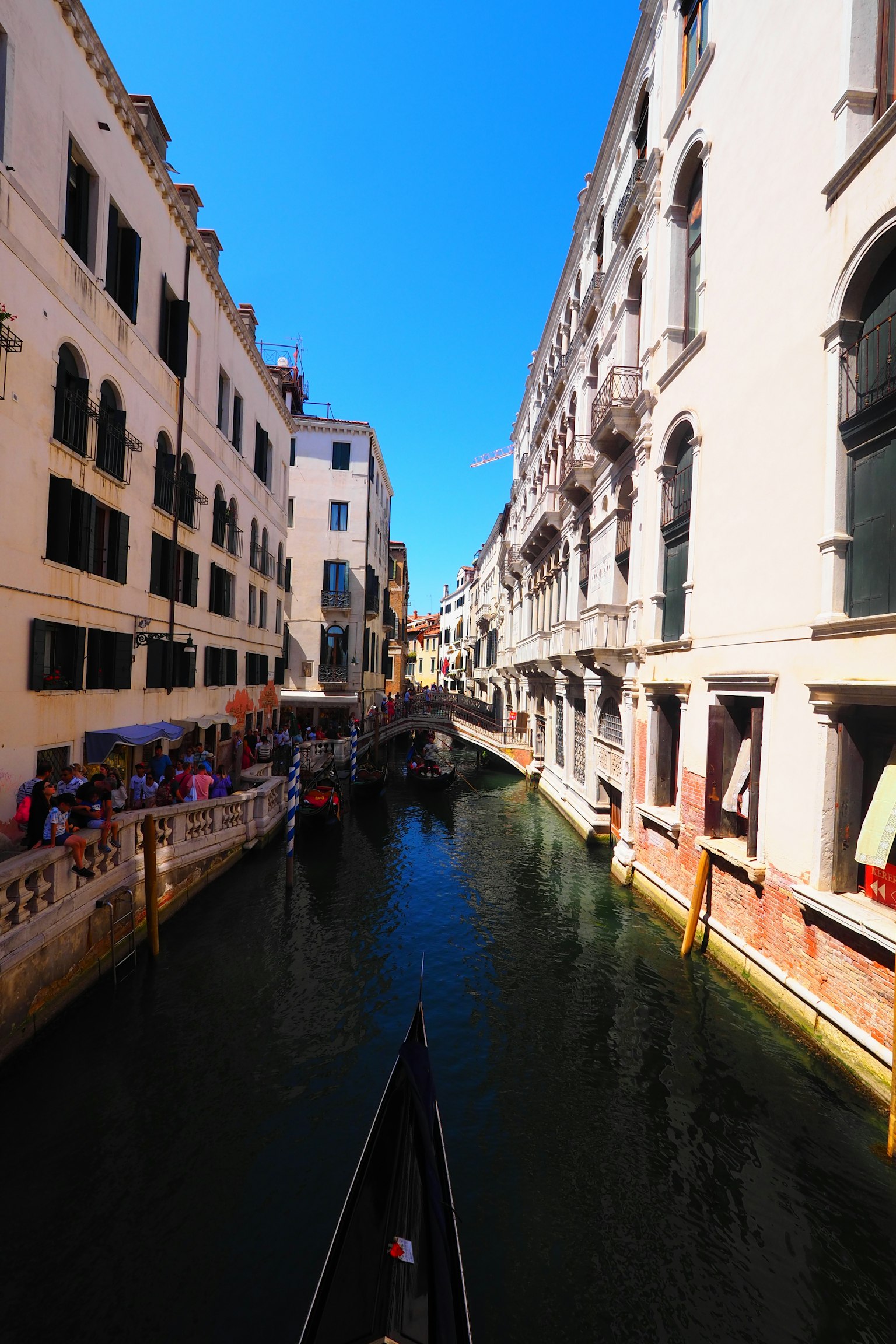 Vista de un canal veneciano con cielo azul brillante y edificios blancos