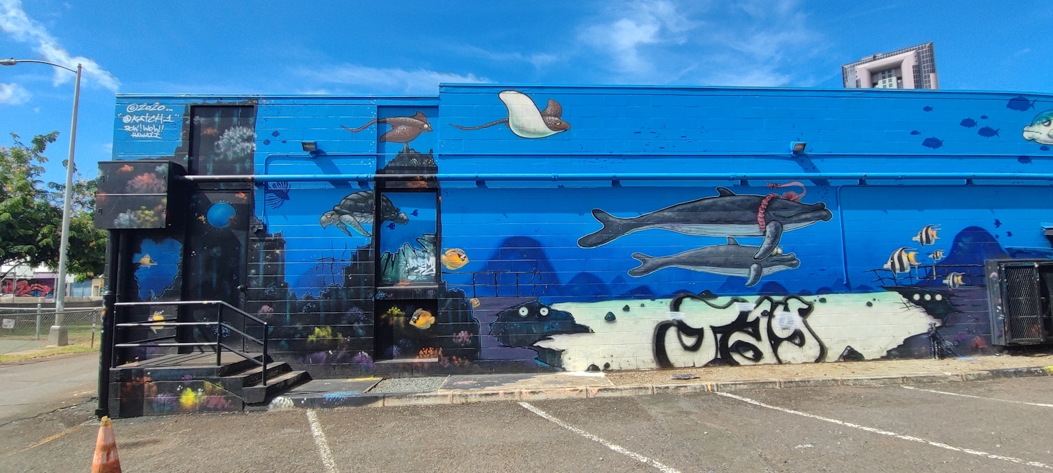 Mural biru cerah yang menggambarkan makhluk laut, termasuk lumba-lumba dan ikan yang berenang