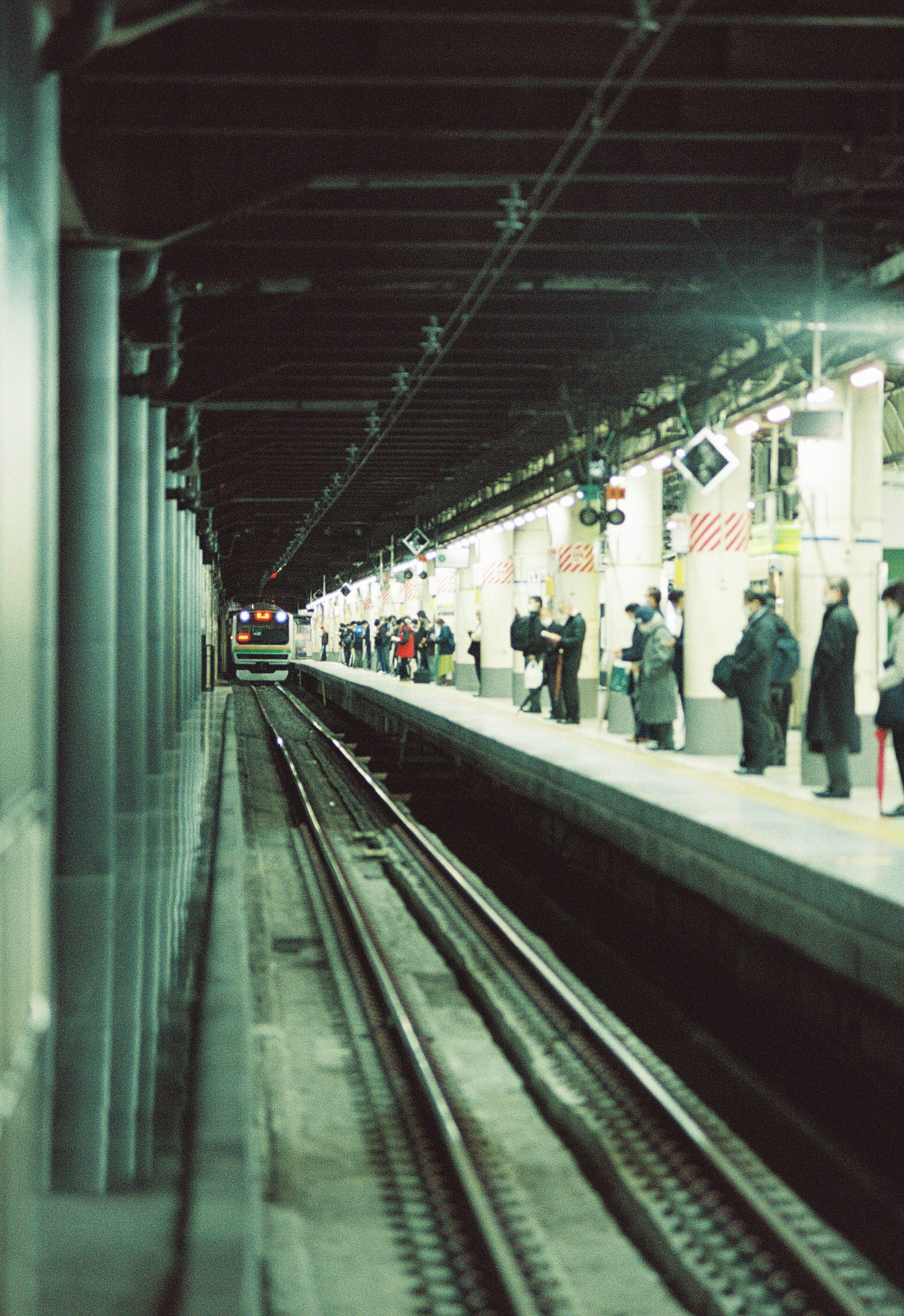地下鉄駅のプラットフォームに立つ人々と線路の視界