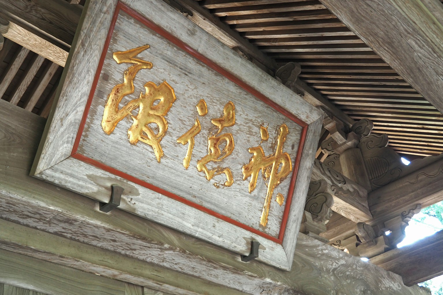 一块古老的神社标志，上面有金色字符