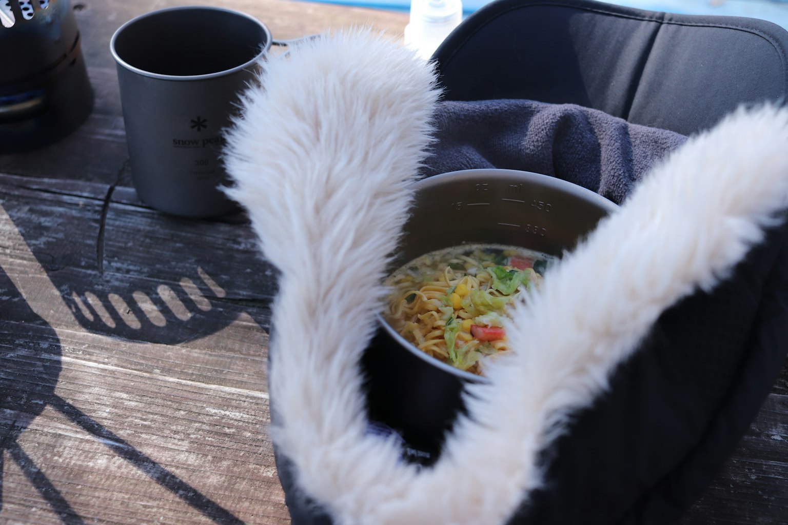 Une casserole de nouilles avec des légumes colorés entourée d'une poignée en fourrure dans un cadre de camping