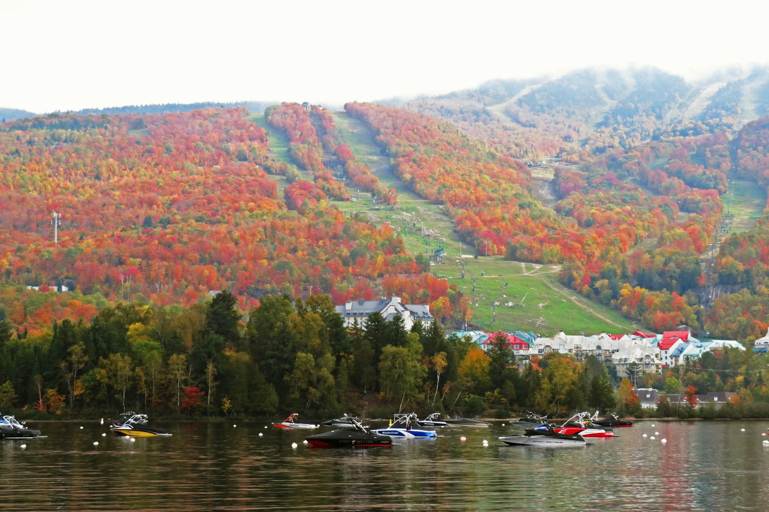 Beau paysage d'automne avec un feuillage coloré recouvrant les montagnes et des bateaux flottant sur le lac