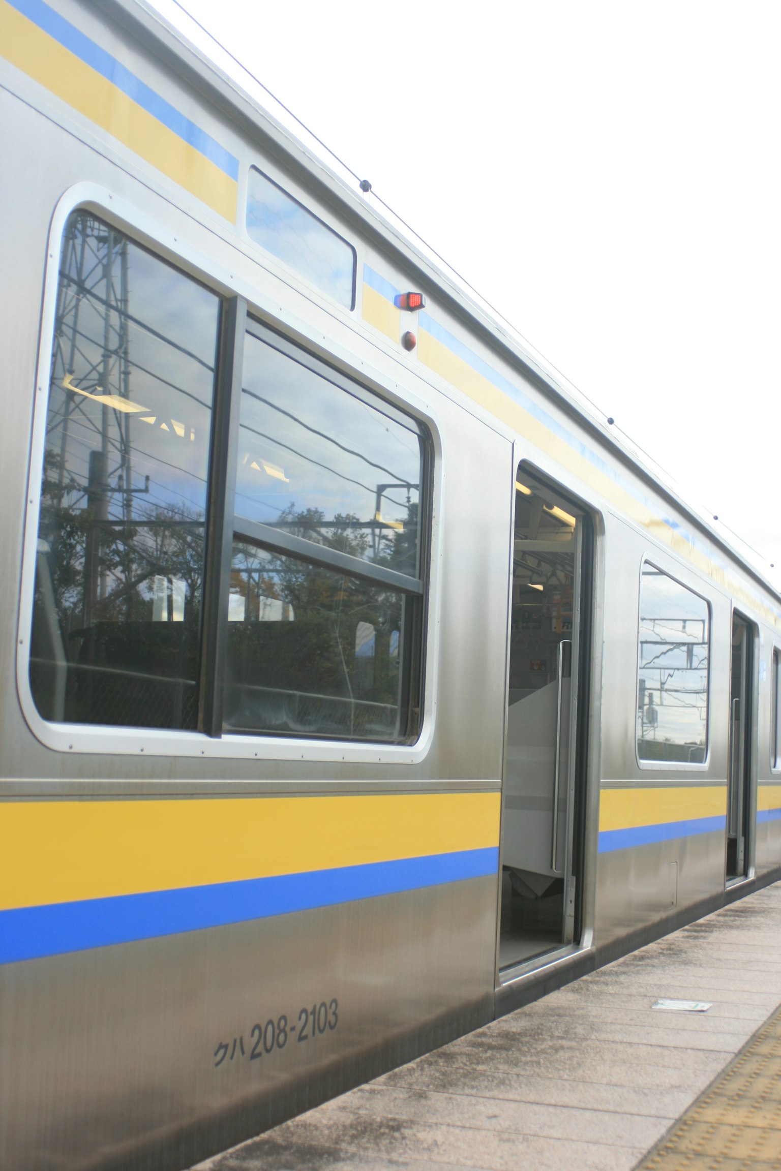 Vista laterale di un treno argento con strisce blu e gialle