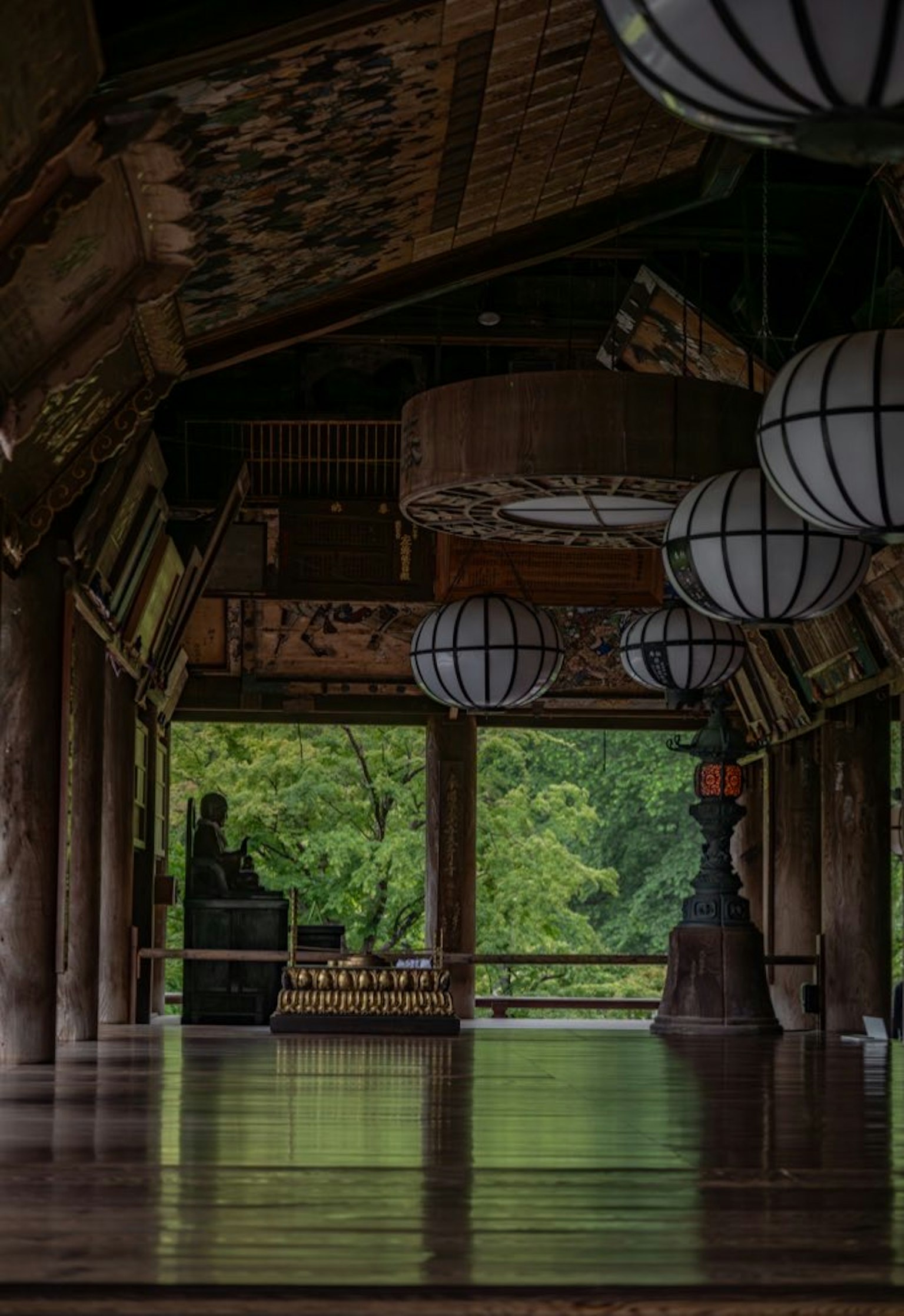 Interior bangunan tradisional Jepang dengan lentera kertas dan lantai kayu dengan pemandangan hijau