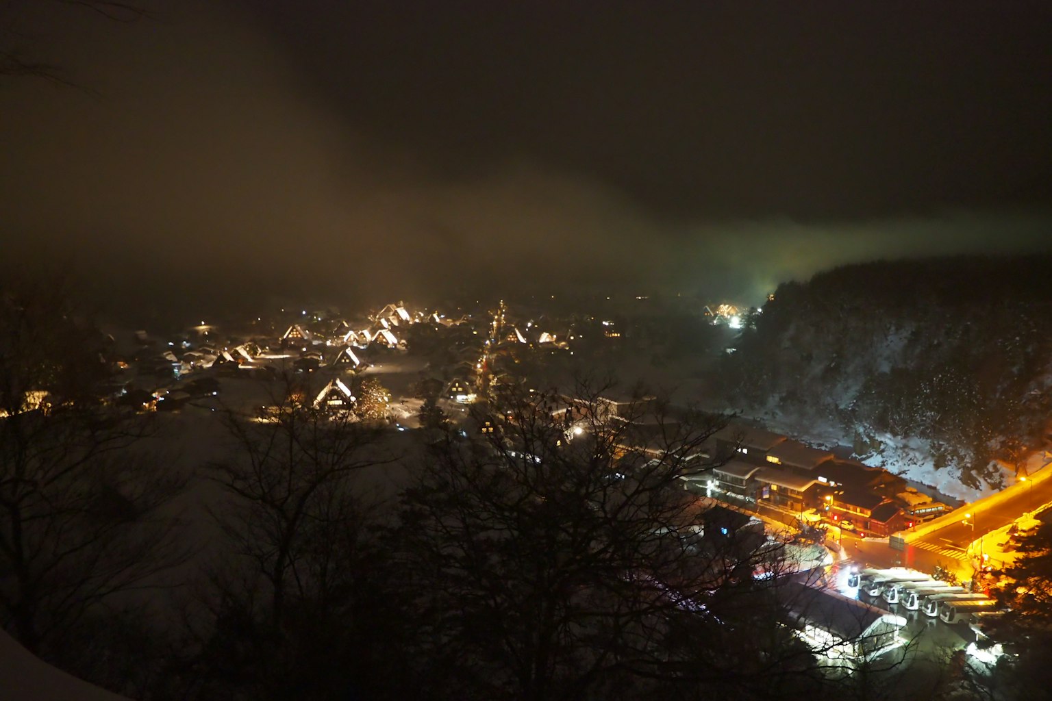 A picturesque night view of a town illuminated by lights with a misty atmosphere