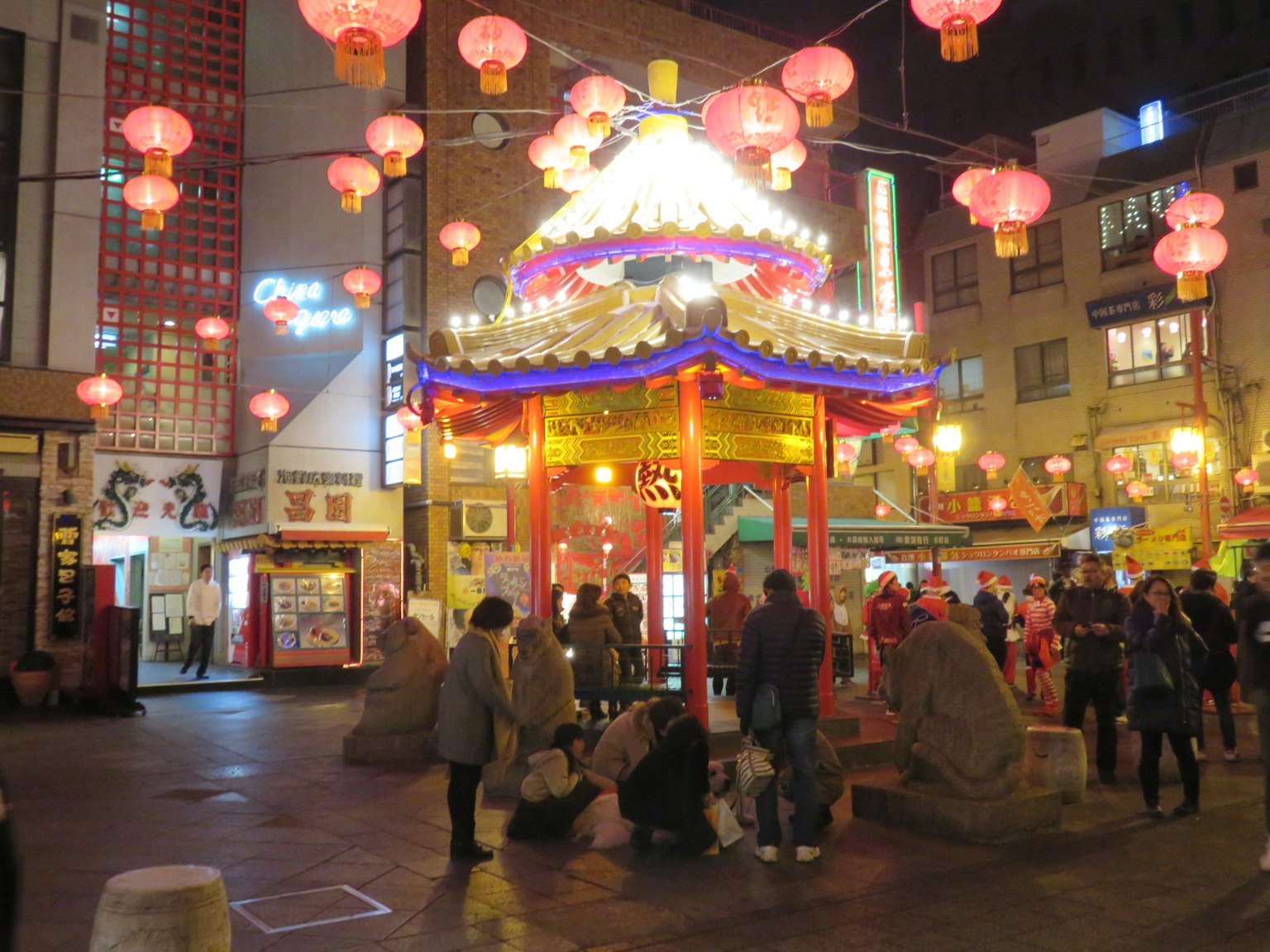 Vibrant lanterns illuminate a lively street corner with people gathering