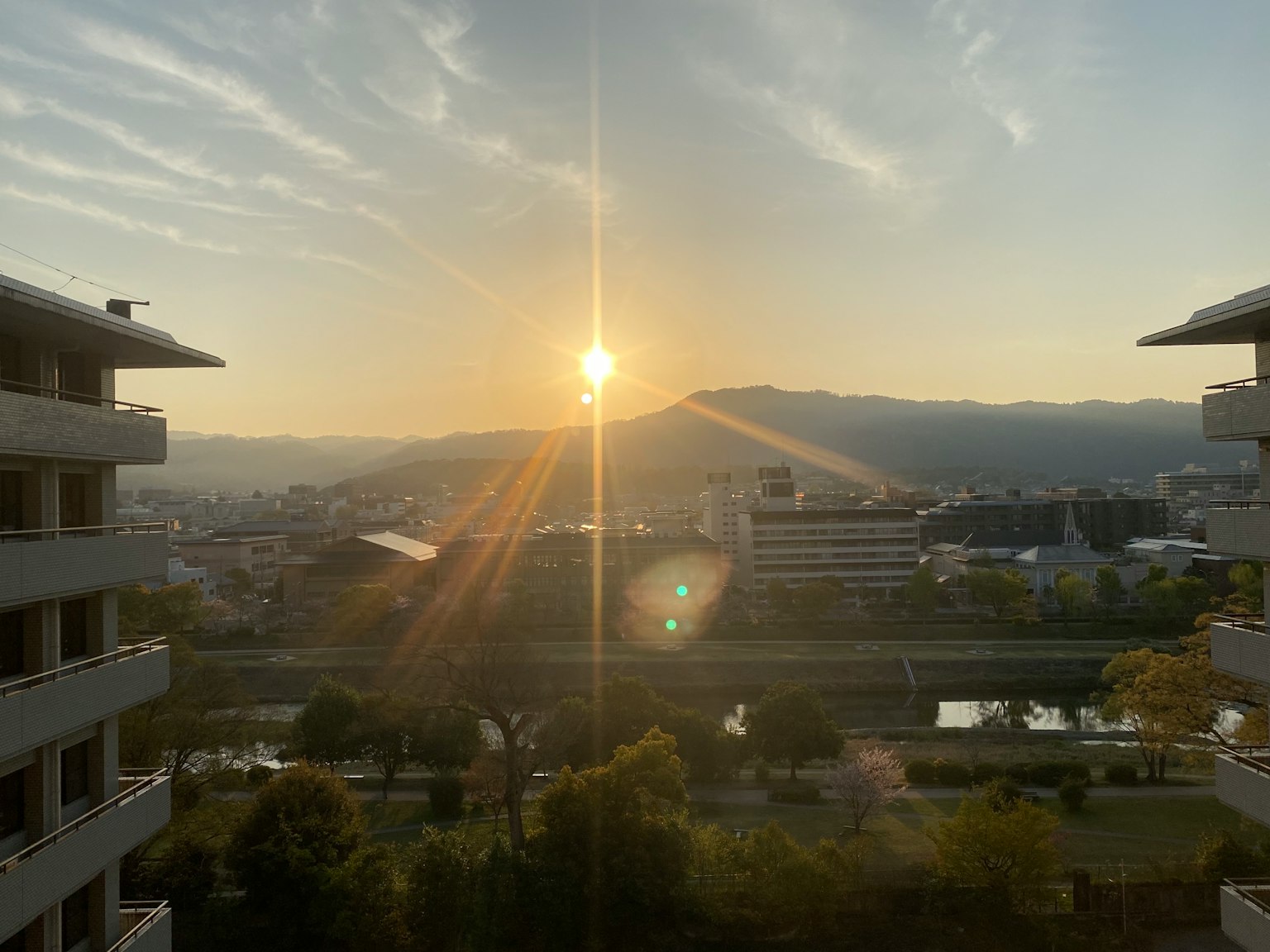 Stadtlandschaft bei Sonnenuntergang mit Sonnenlicht über Bergen und Fluss