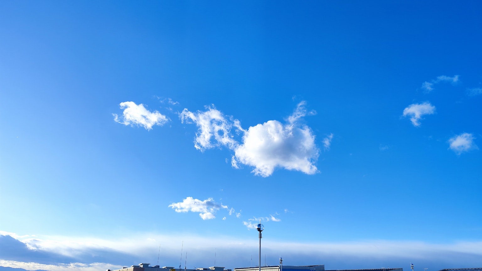 Nuvole bianche che fluttuano in un cielo blu con silhouette di edifici