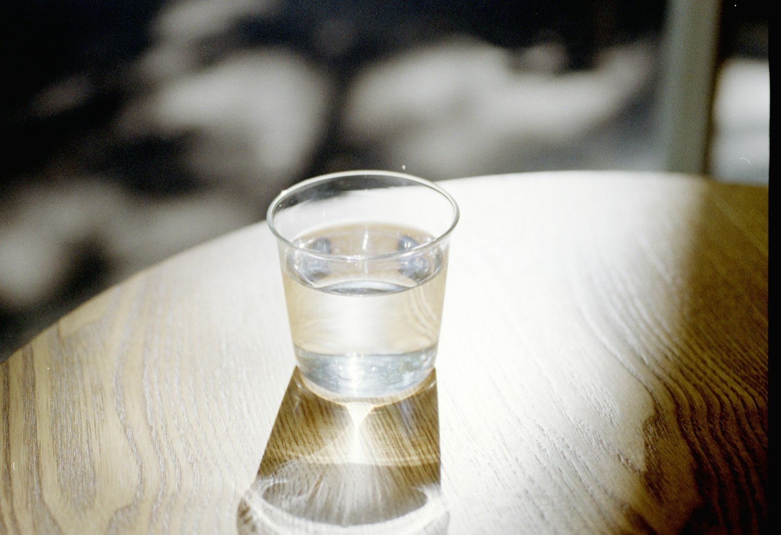 透明なコップに入った水が木のテーブルの上に置かれている