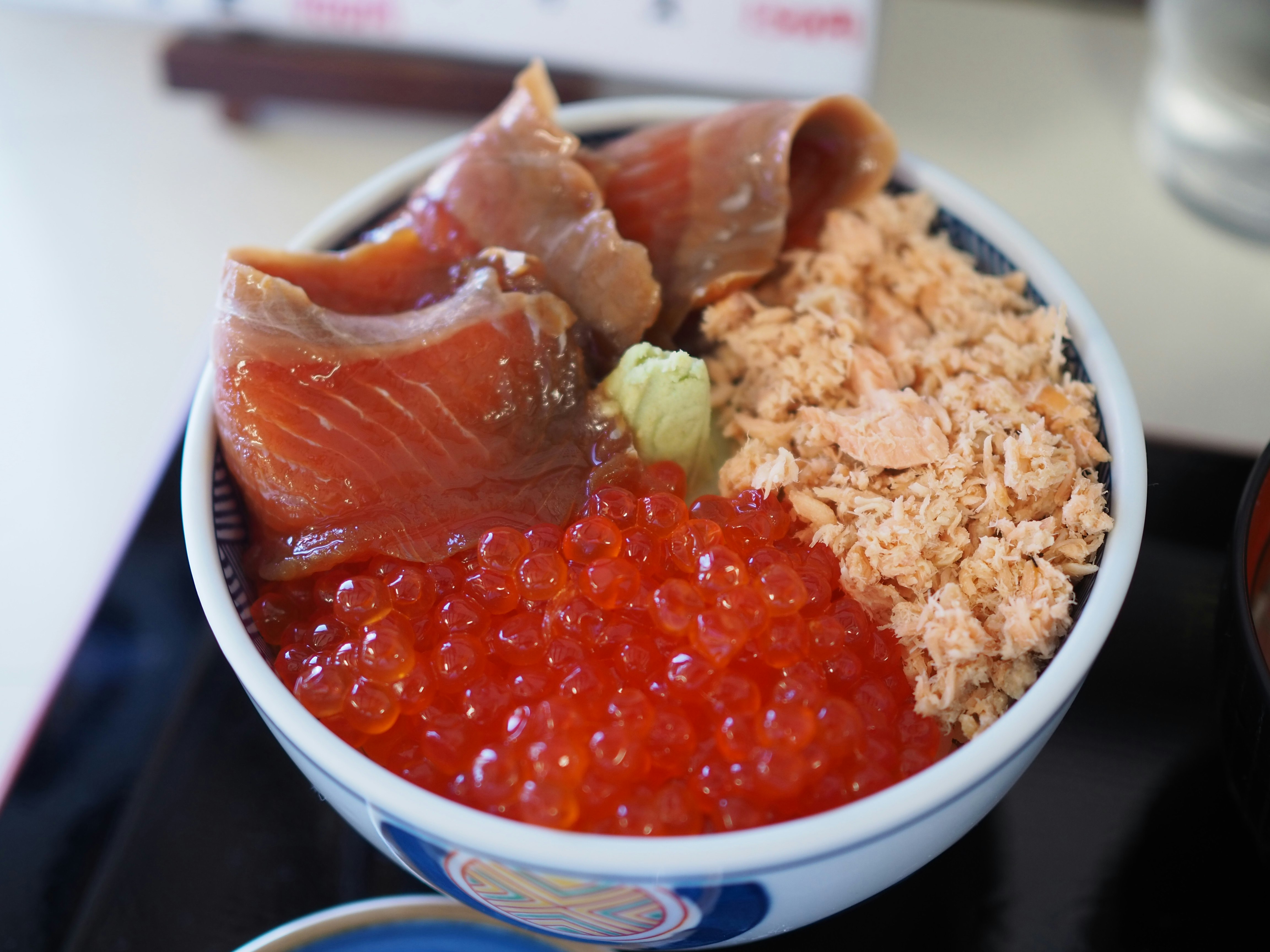 Tampilan dekat semangkuk nasi dengan topping merah, salmon, dan furikake