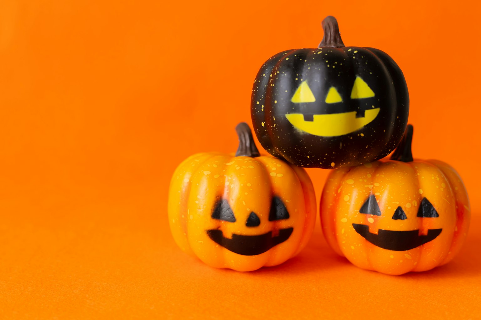 Zucche colorate a tema Halloween disposte su uno sfondo arancione