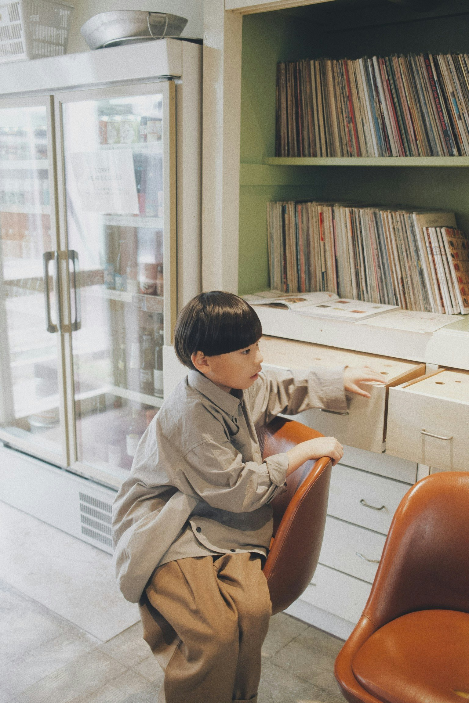 子供が椅子に座りながら棚の引き出しを開けている室内のシーン