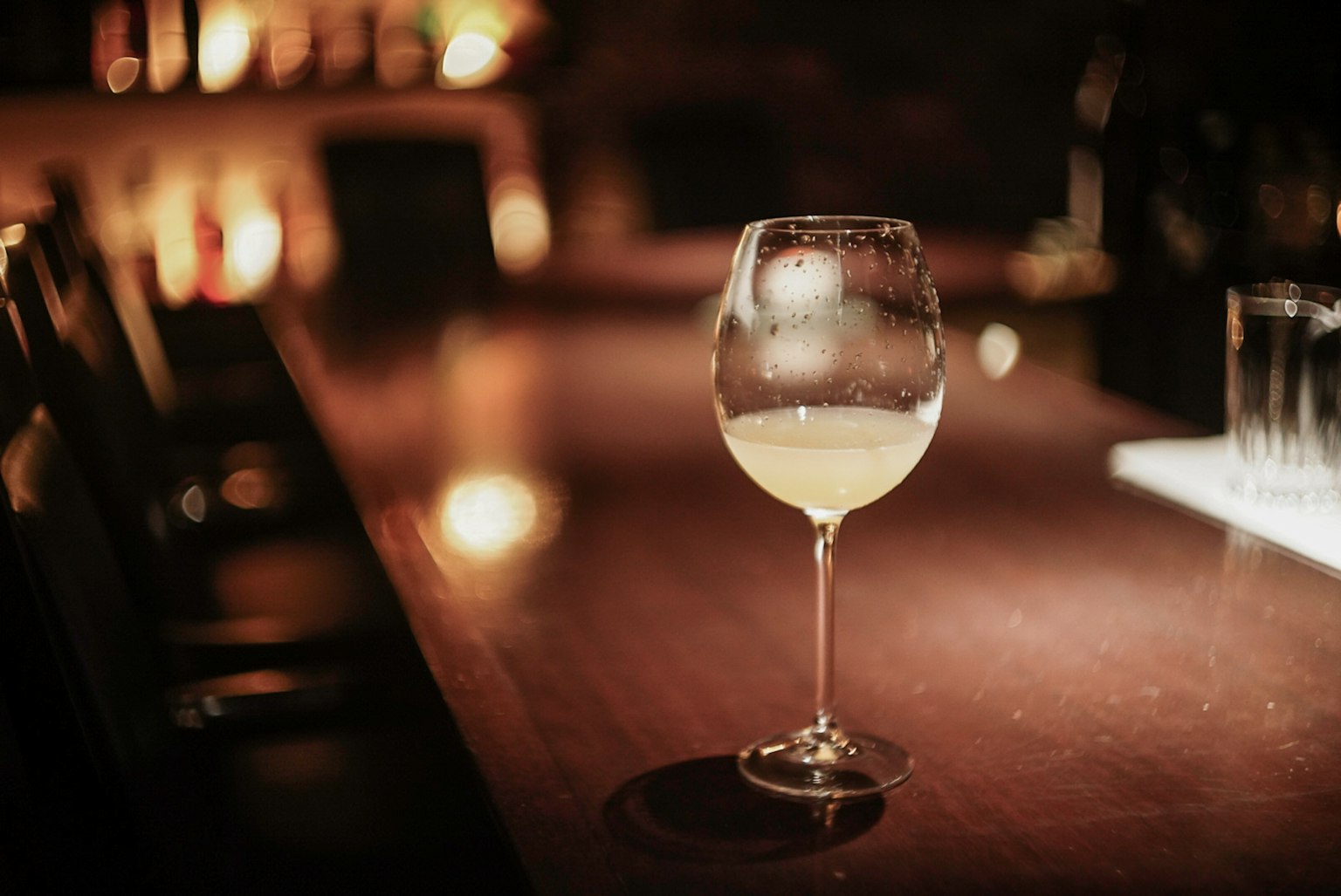 Cocktail in einem Weinglas auf einer schwach beleuchteten Bar