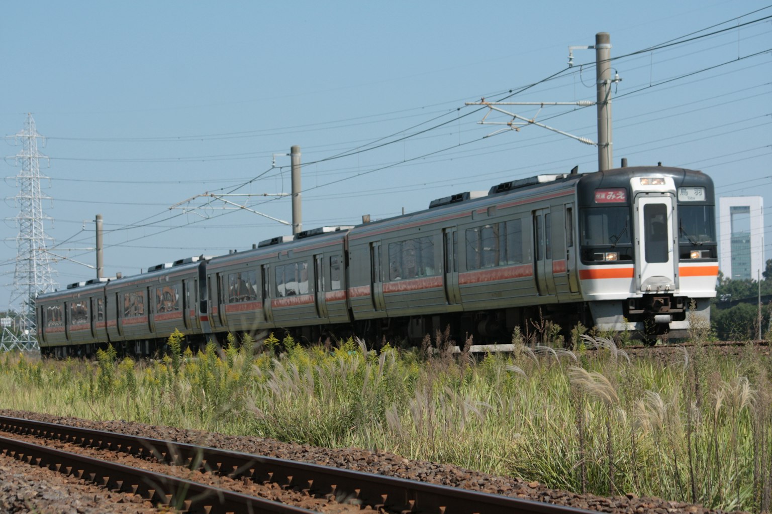 Un tren negro que corre bajo un cielo azul con hierba alrededor