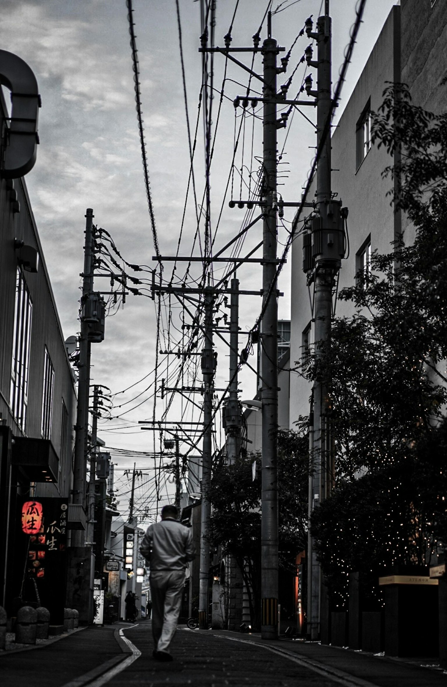 一個人在昏暗的街道上走，交錯的電線