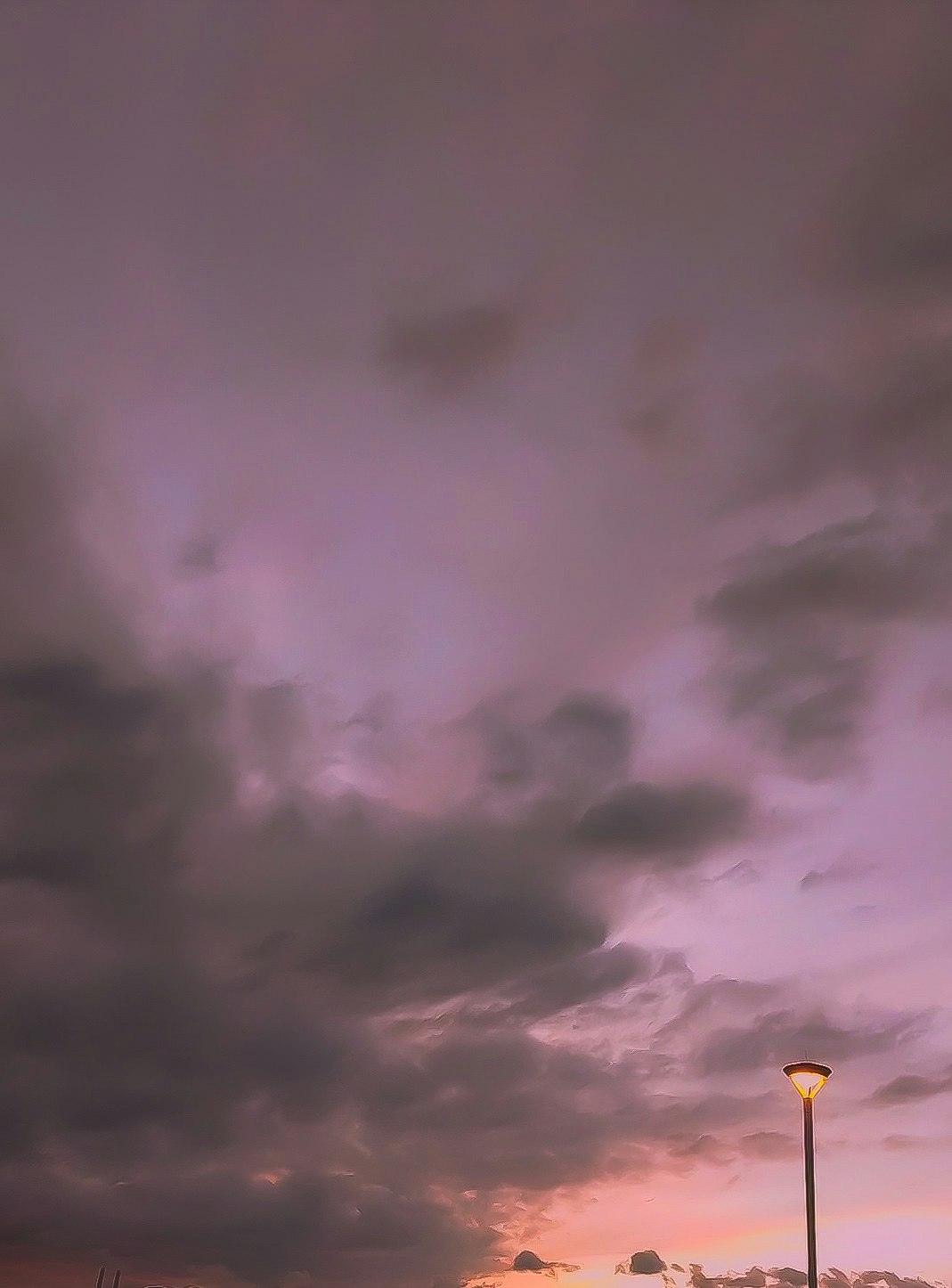夕焼け空に近づく雨雲と街灯
