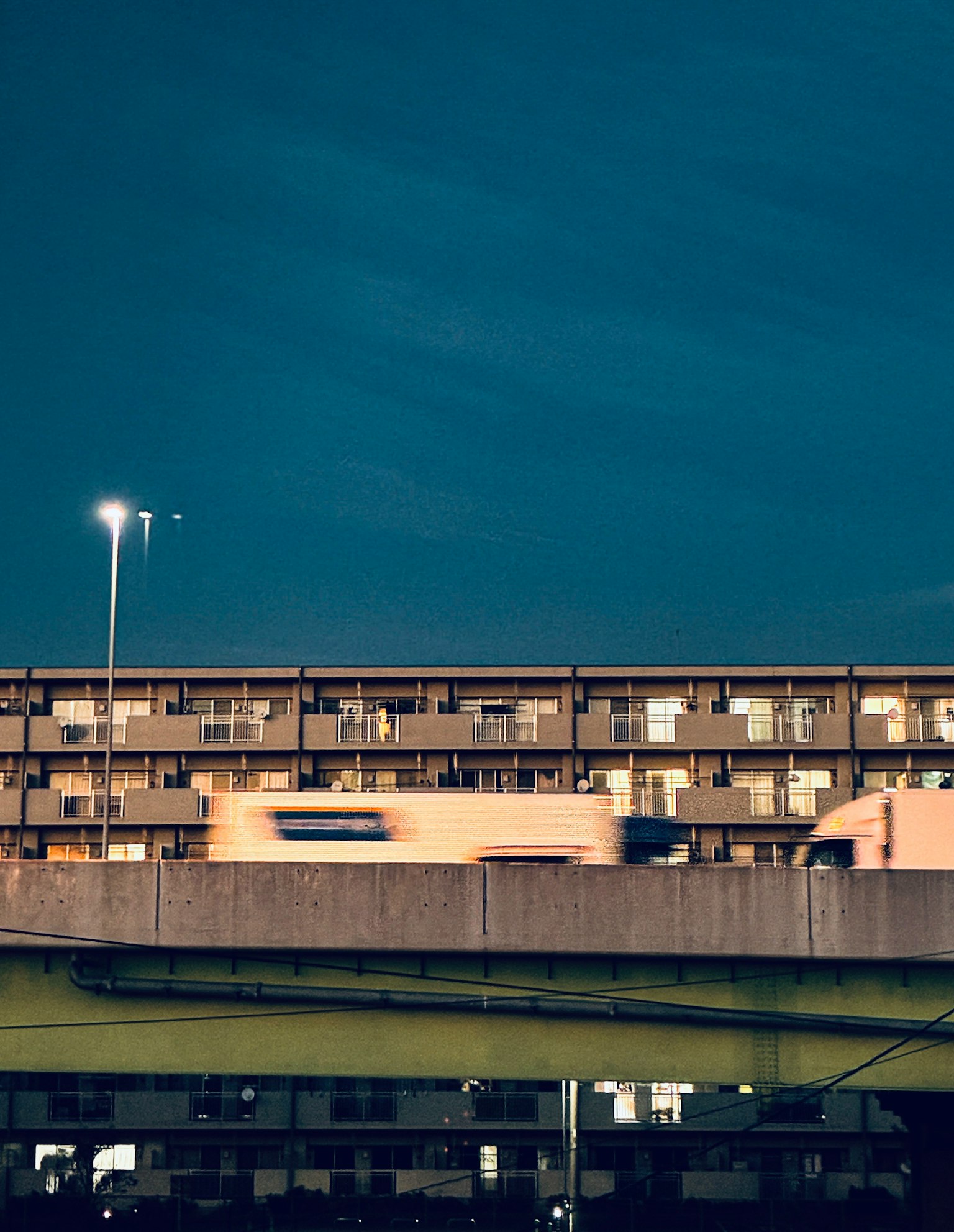 夜の都市風景 高層アパートと道路の下を通る車の光