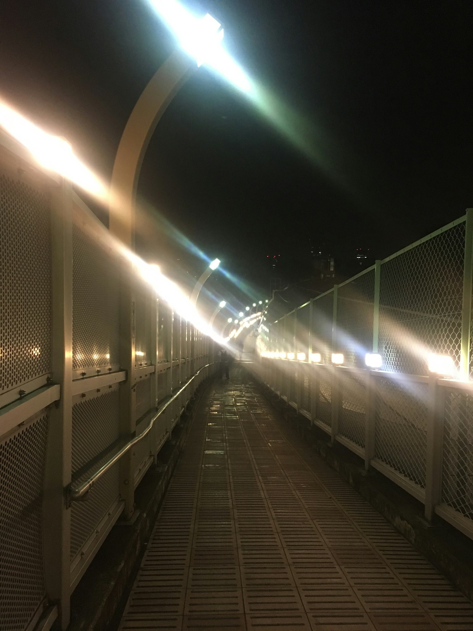 ทางเดินที่มีแสงสว่างบนสะพานในเวลากลางคืน