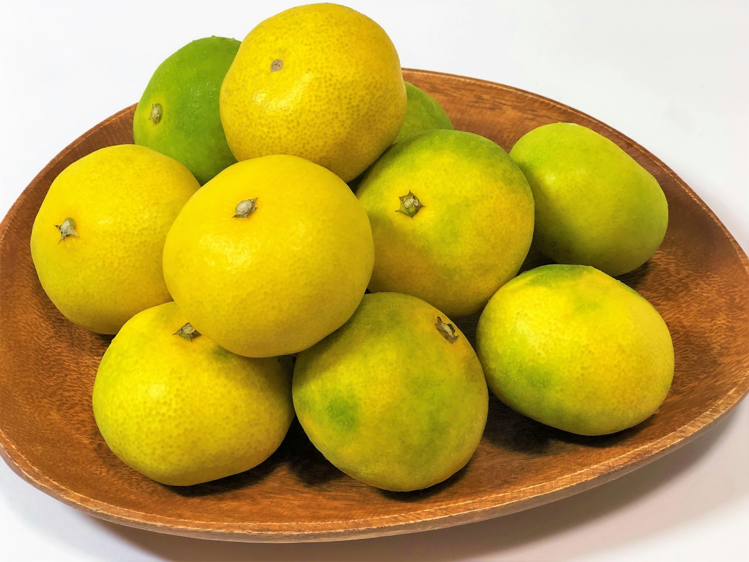 Un tas de fruits d'agrumes jaunes et verts sur une assiette en bois