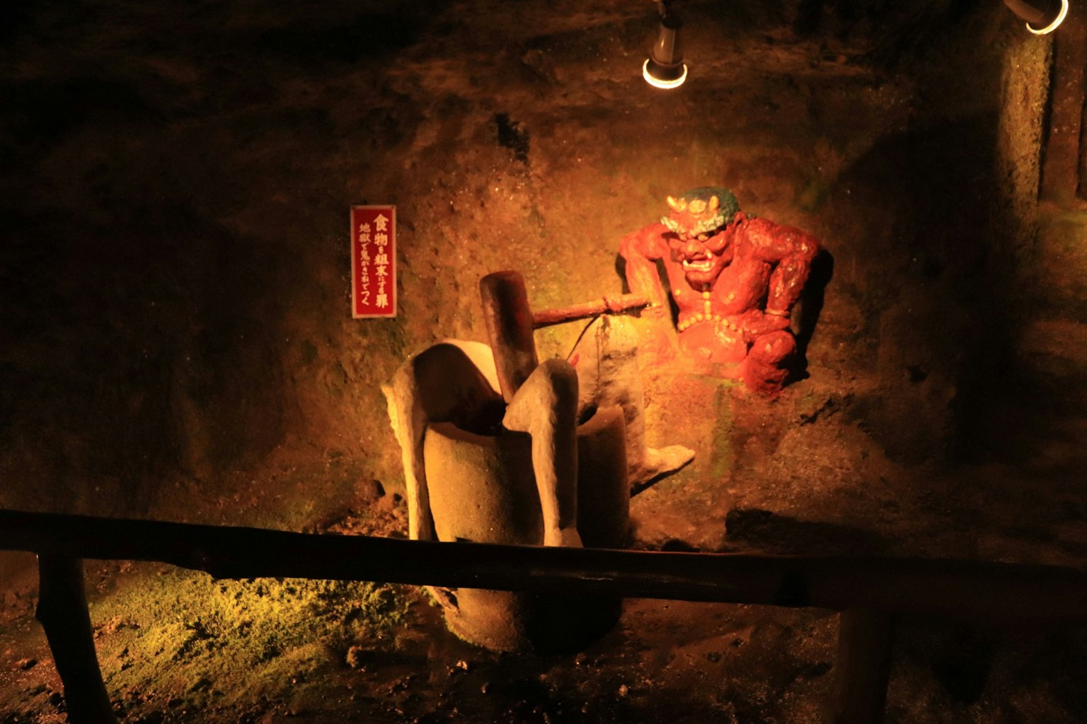 Una statua di demone rosso in una grotta che colpisce una figura bianca con un martello