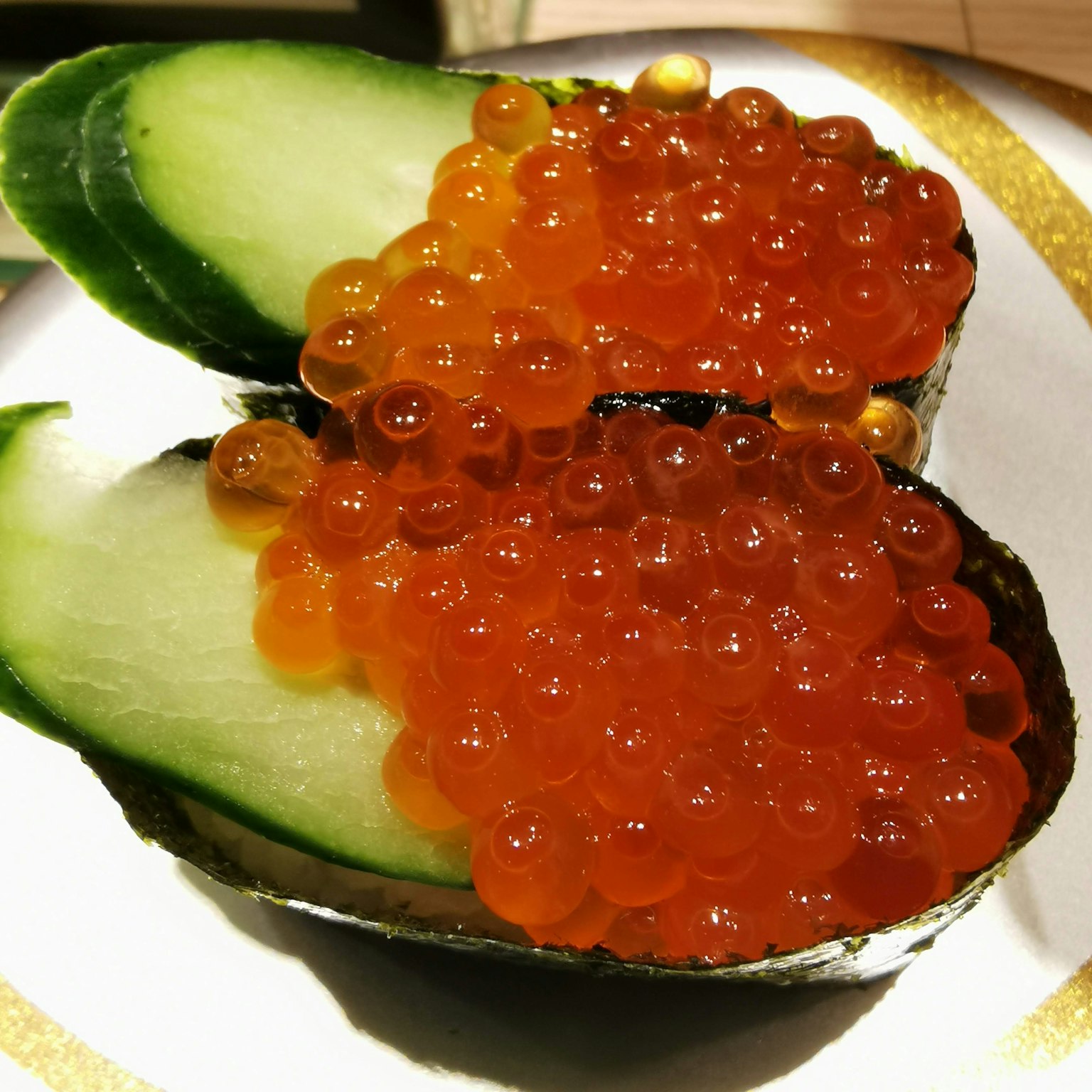 Halbes Avocado mit Lachsrogen und Gurkenscheiben belegt