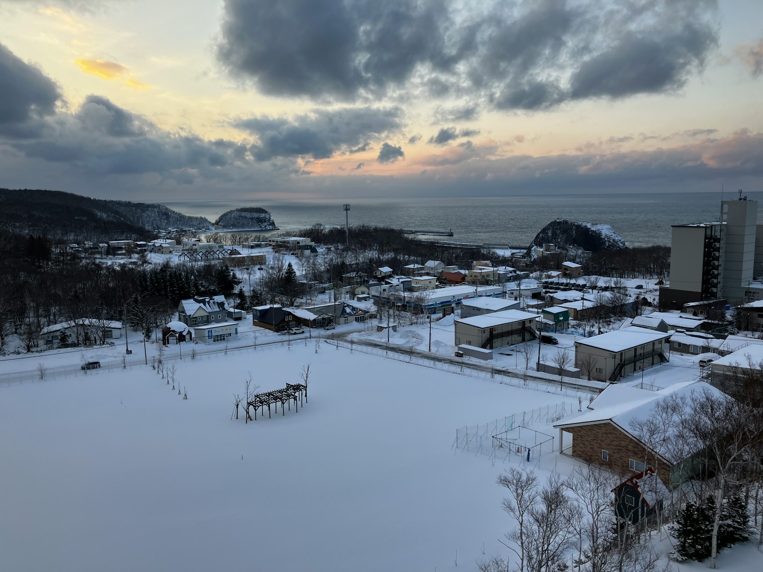 被雪覆盖的城镇与海洋景色日落和多云的天空
