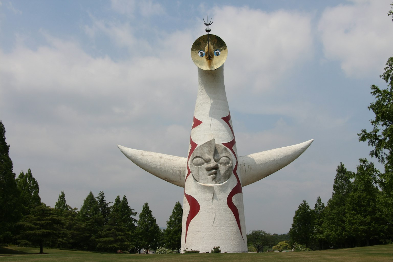 The Tower of the Sun sculpture stands under a blue sky