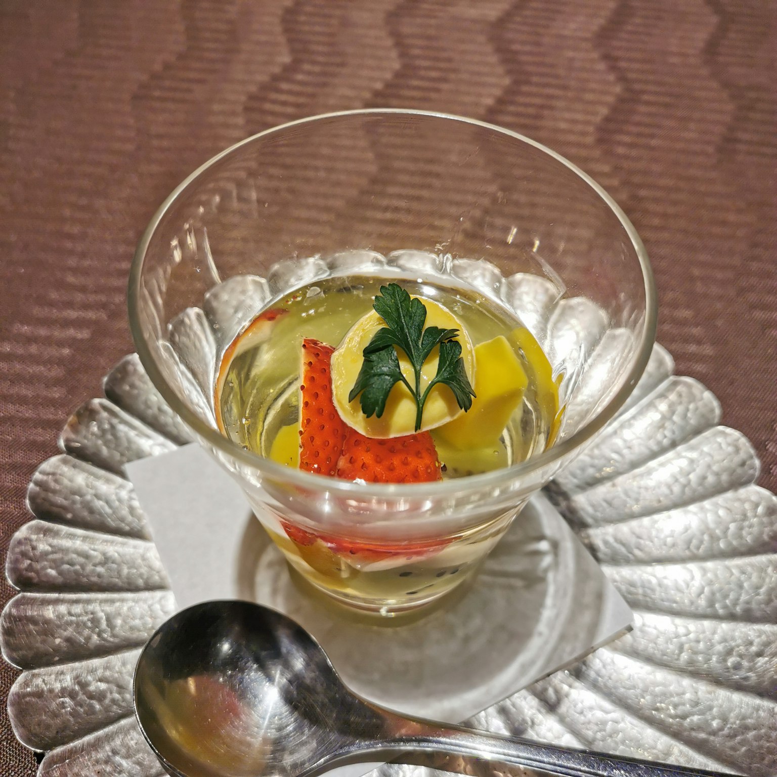 Ein transparenter Dessertbecher mit Fruchtgelee und einem Minzblatt