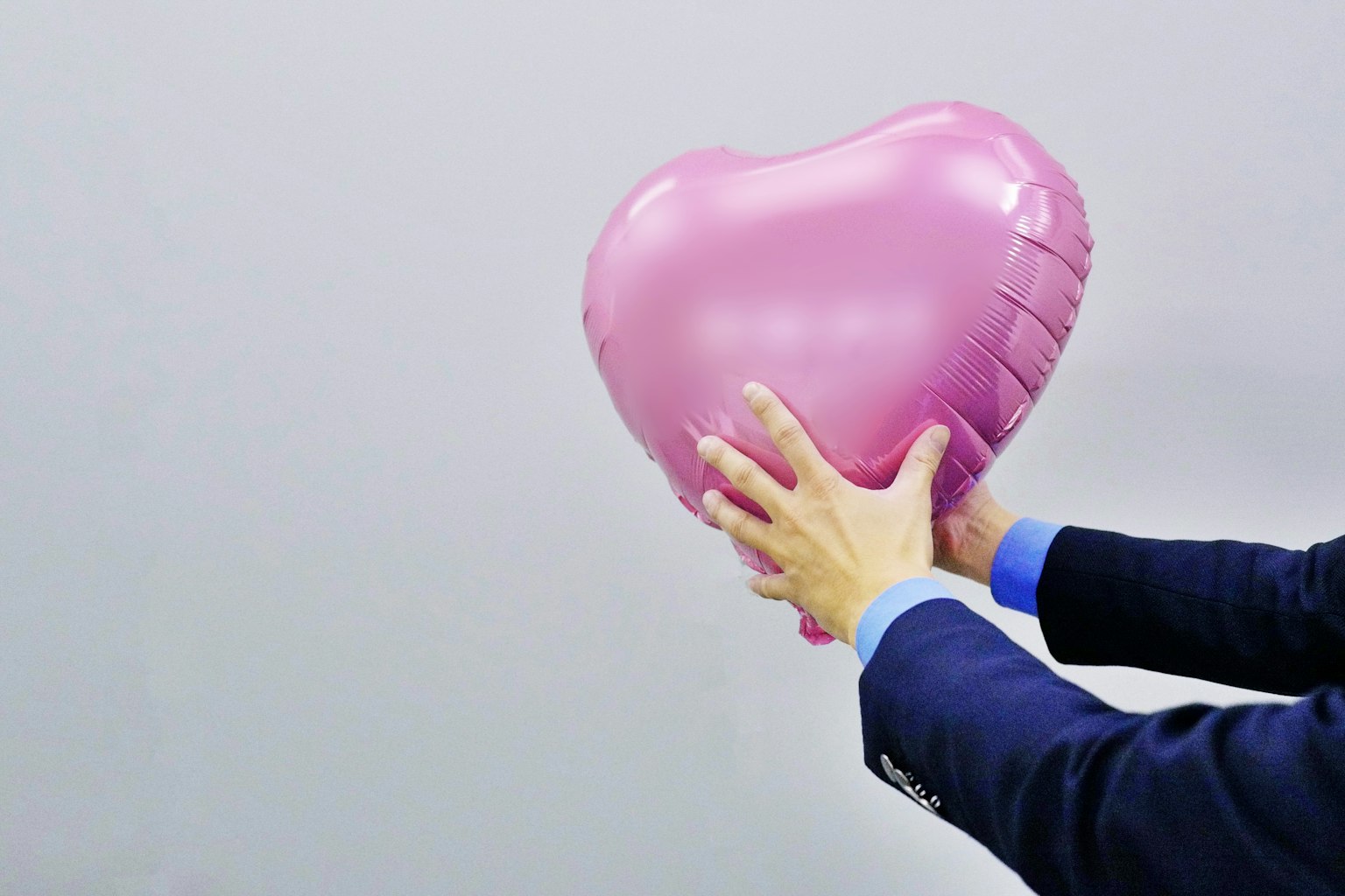 Ein Geschäftsmann hält einen rosa Herzballon