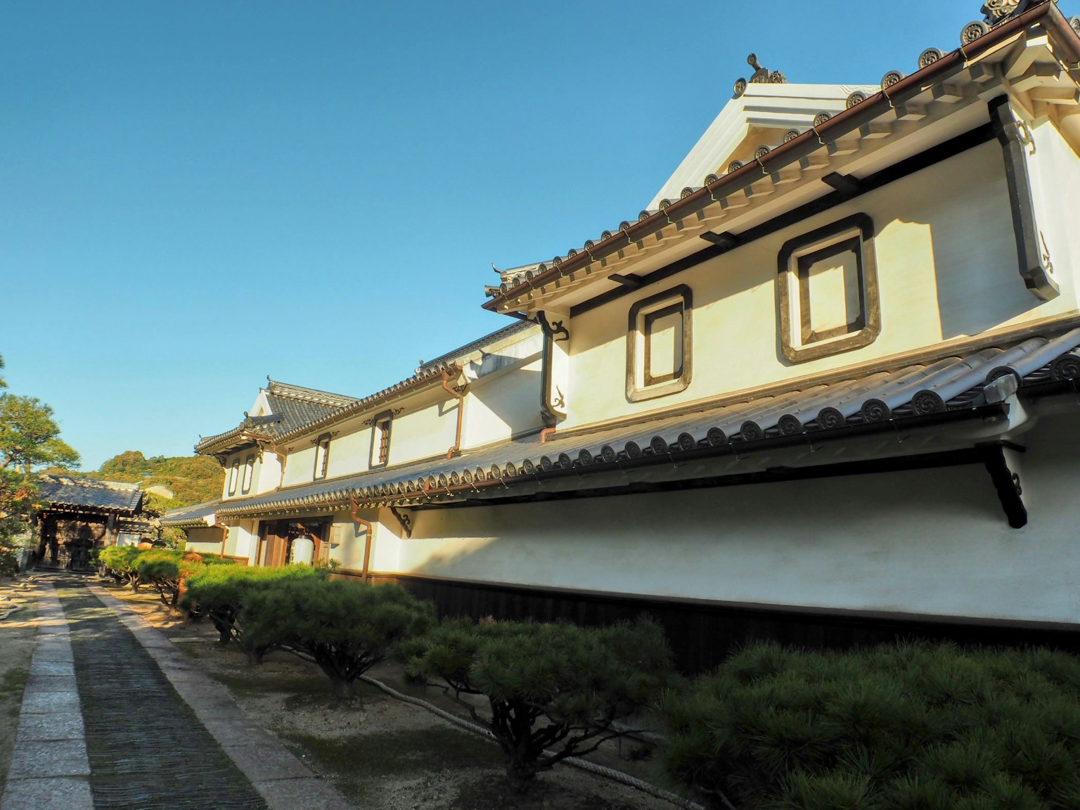 Traditional Japanese house with white walls featuring a green garden and stone pathway