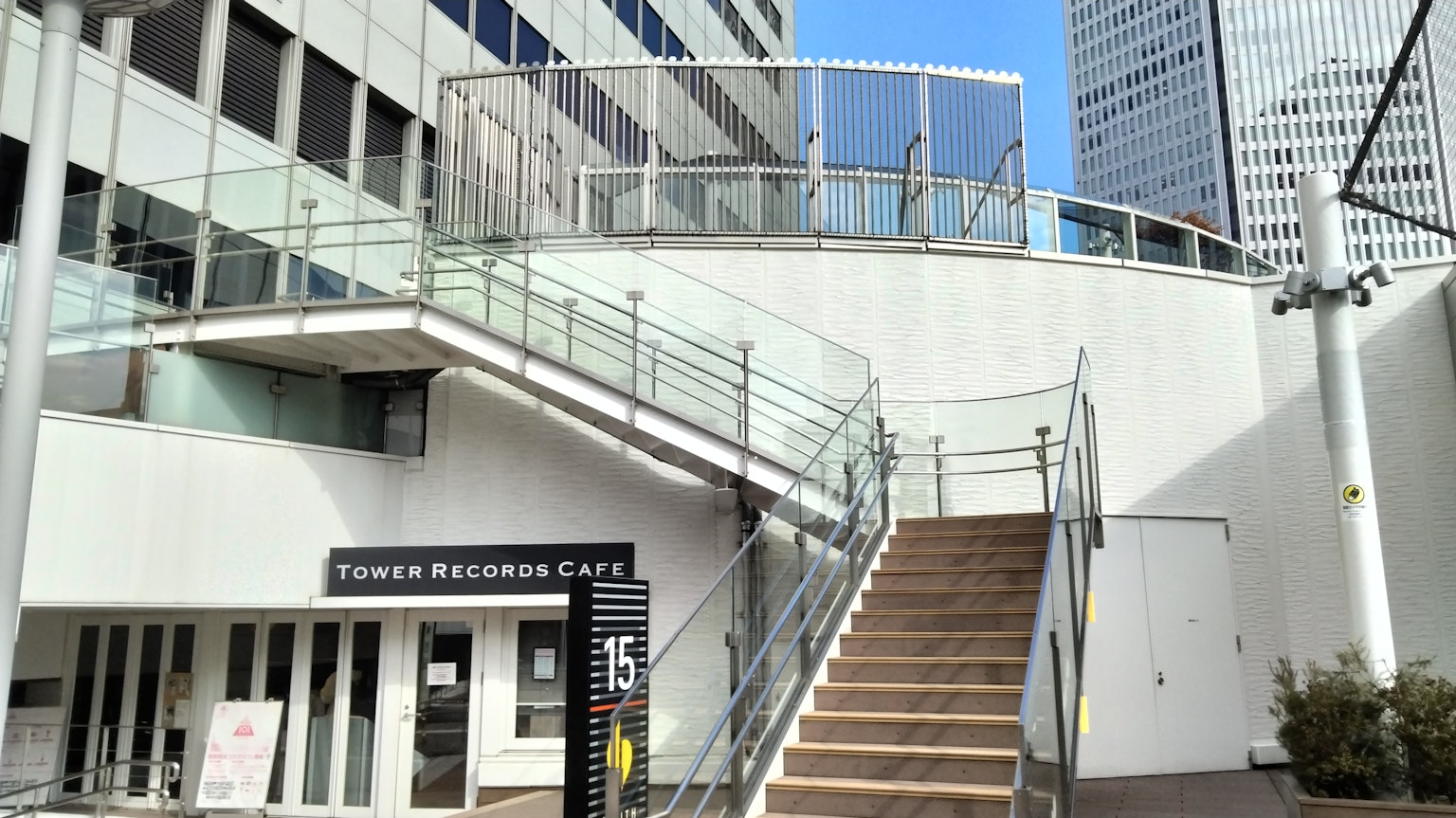 Escalera con barandilla de vidrio y pared exterior blanca