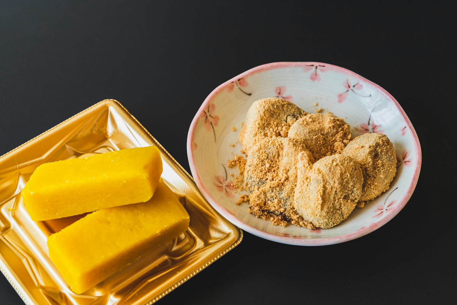 黃色甜點塊和裹著黃豆粉的甜米團放在盤子裡