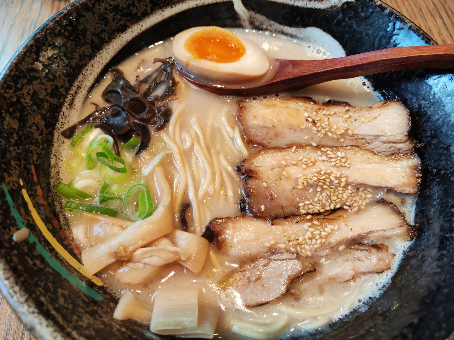 검은 그릇에 담긴 라면 슬라이스 차슈 반숙 계란 파와 참깨