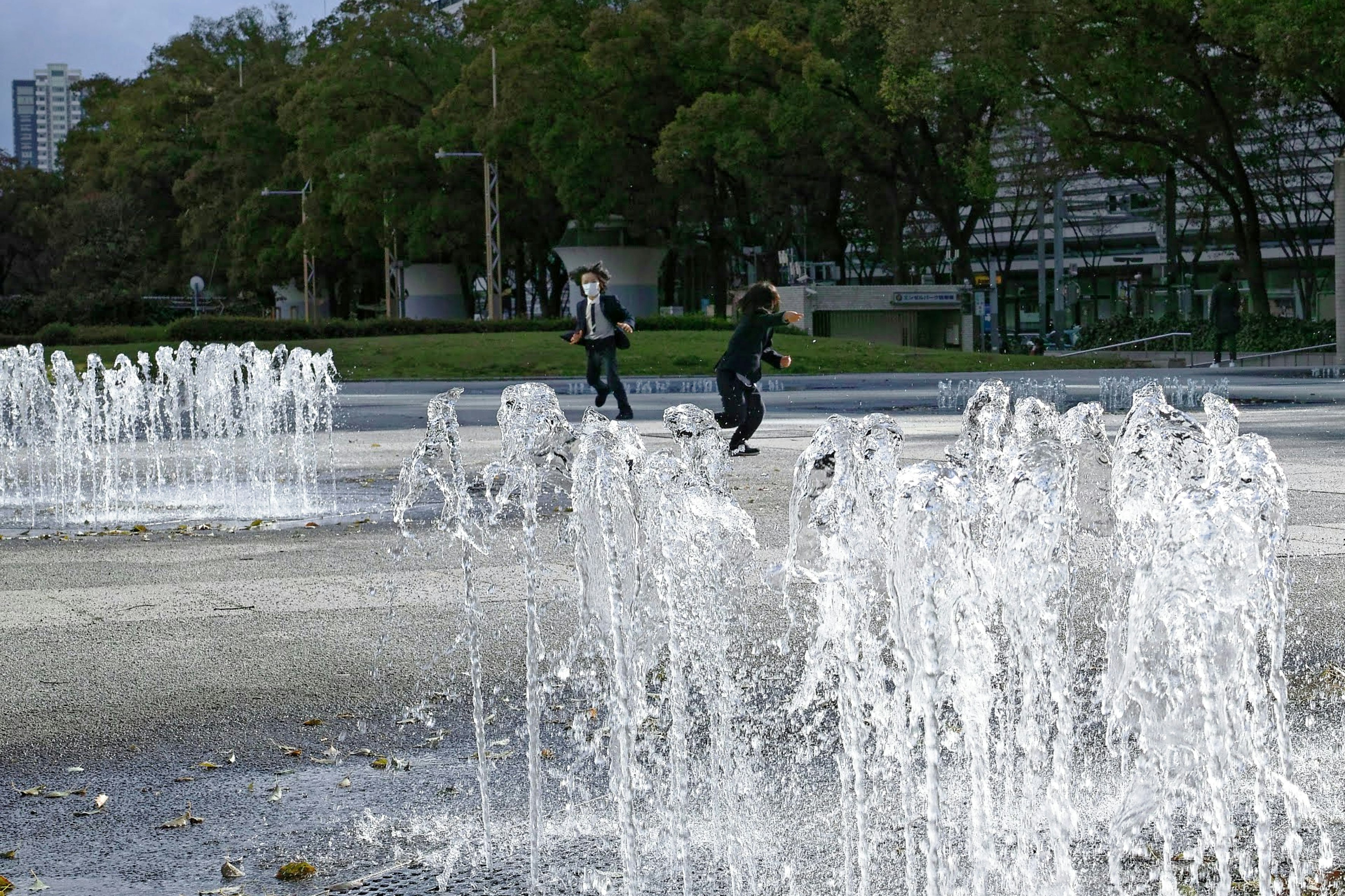 噴水のある公園で遊ぶ正装の少年たち