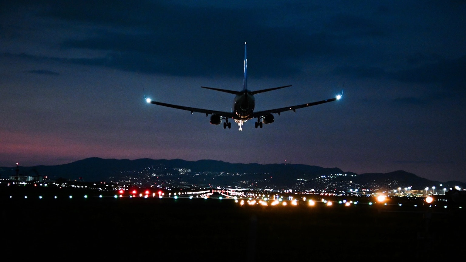 Silhouette d'un avion volant dans le ciel nocturne avec des lumières de la ville