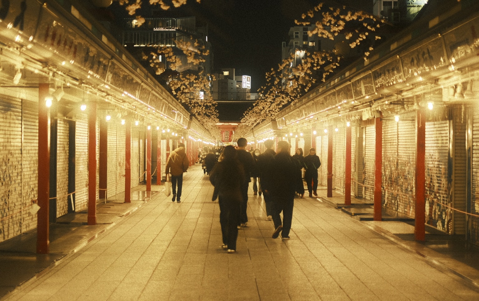 人们在夜间购物街上走，商店灯光闪烁