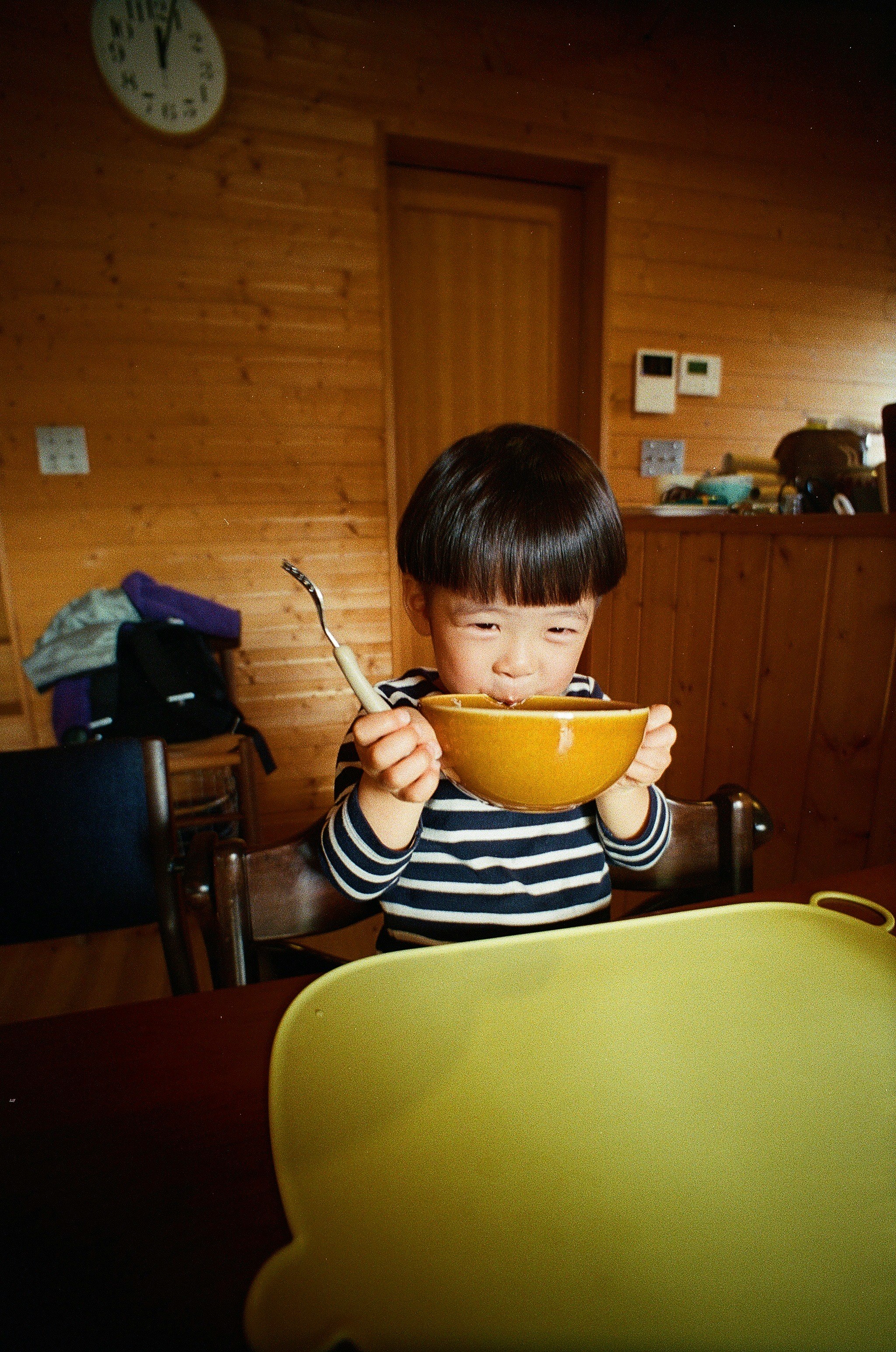 เด็กถือช้อนในห้องไม้ มองชามสีเหลือง