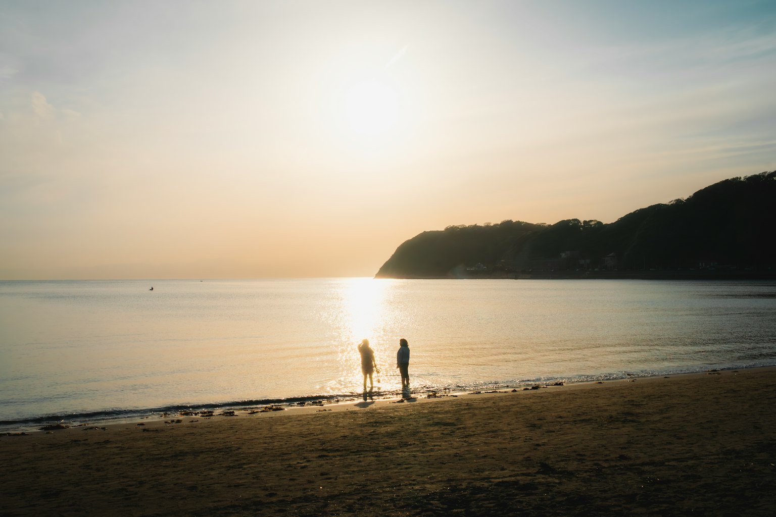 일몰 동안 해변에 서 있는 두 사람의 실루엣