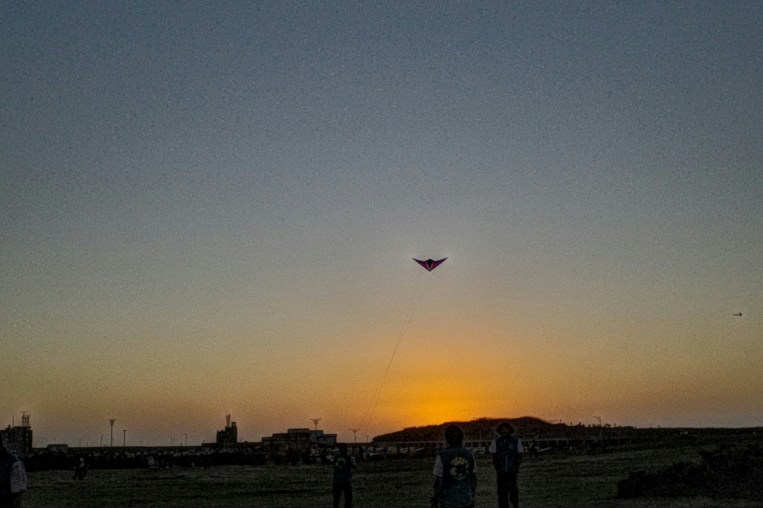 夕日を背景にしたカイトを飛ばす人々のシルエット
