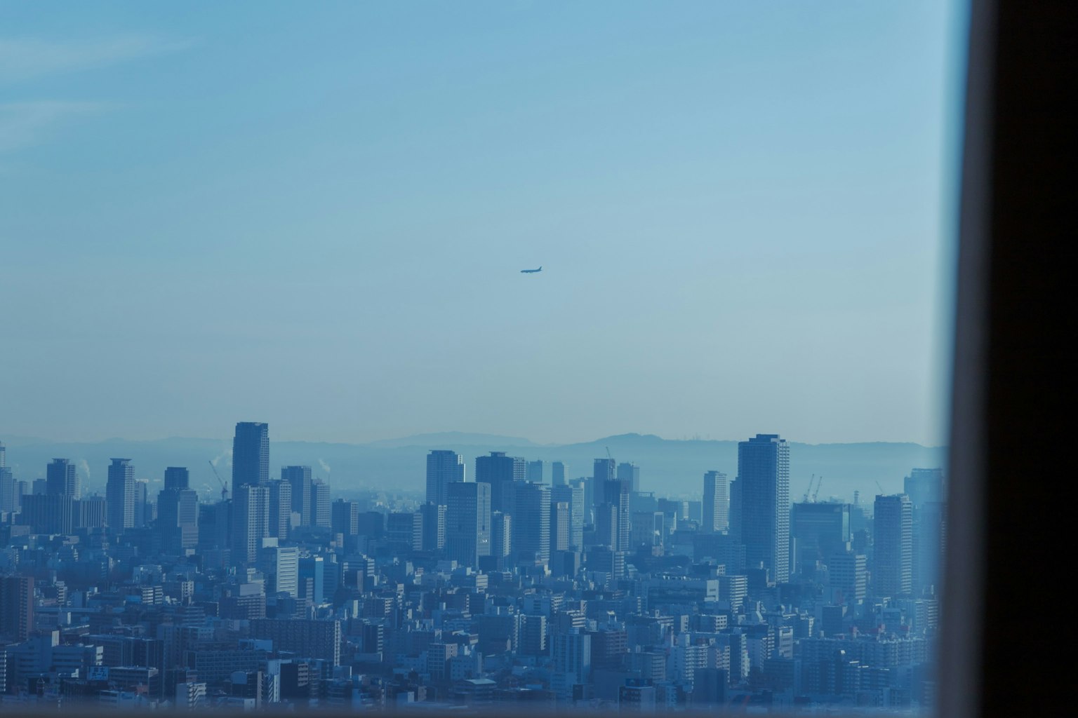Vista panoramica della città sotto un cielo blu con montagne in lontananza