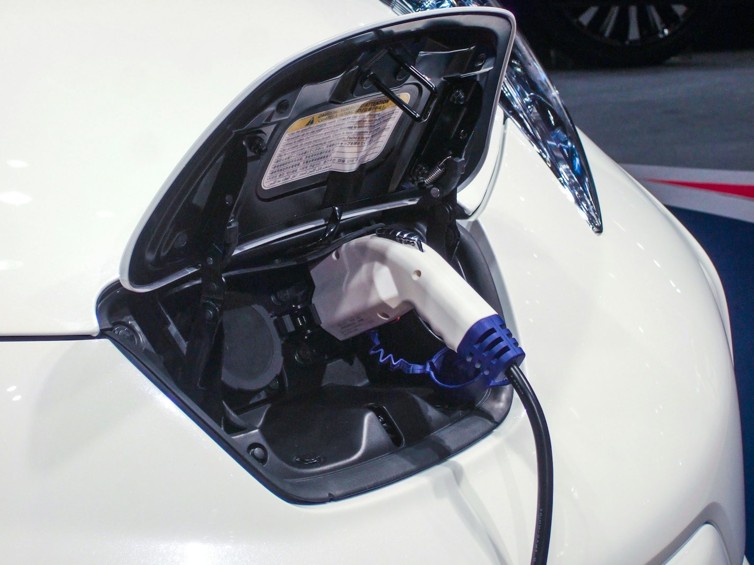 Porta di ricarica di un veicolo elettrico bianco con un cavo di ricarica collegato