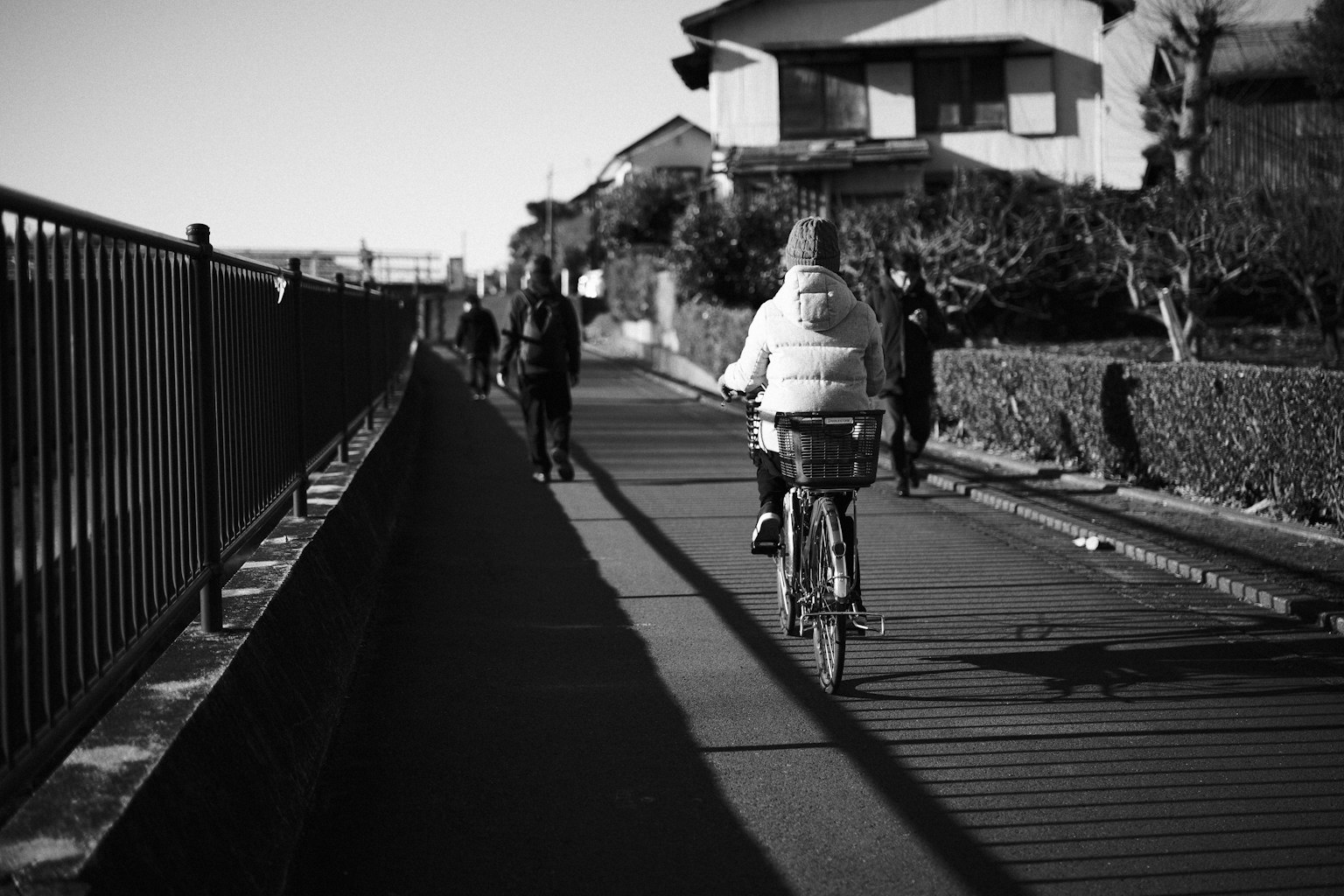 Una persona in bicicletta su una strada in bianco e nero con pedoni