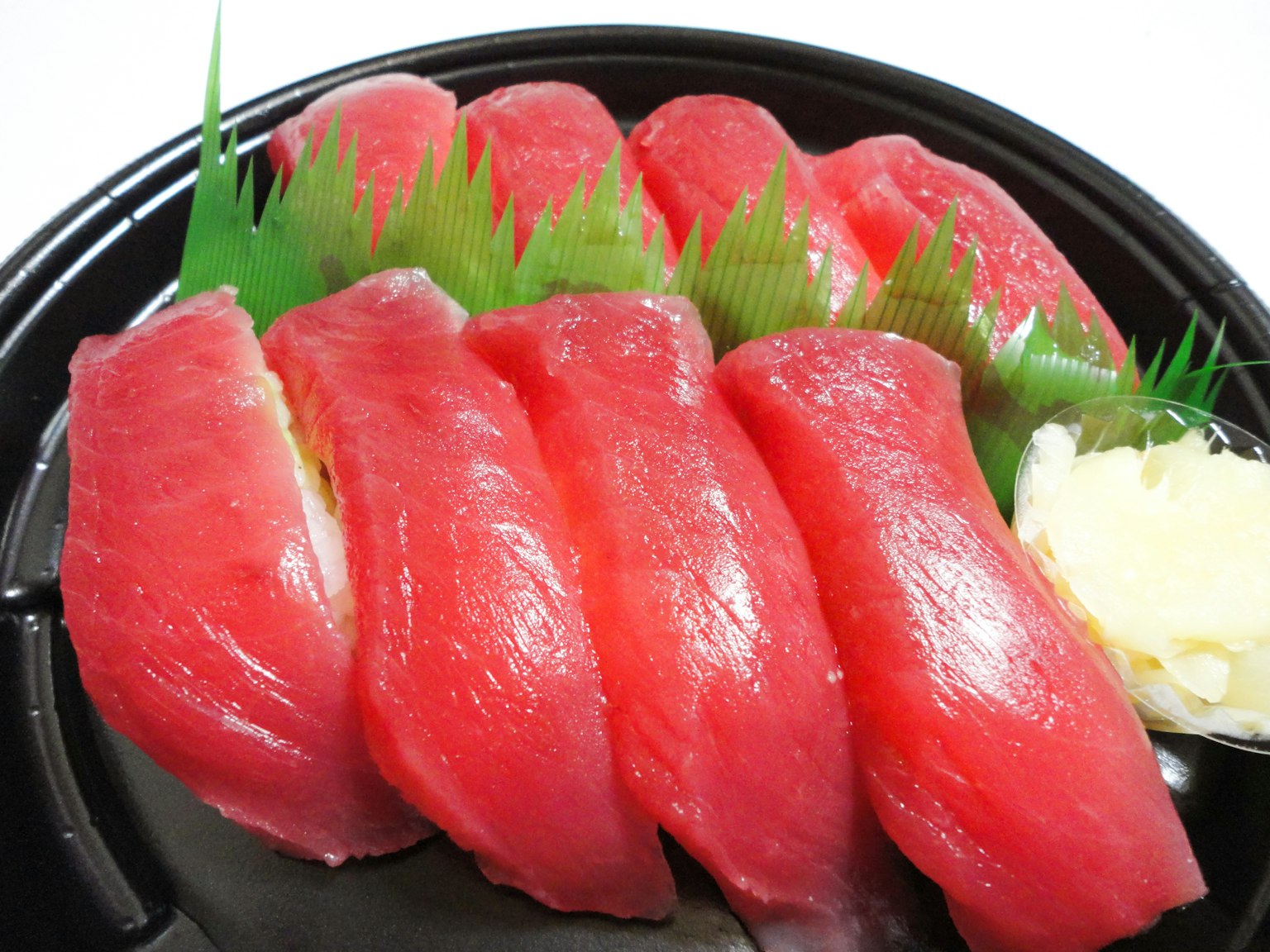Nigiri sushi tuna segar disusun di atas piring hitam