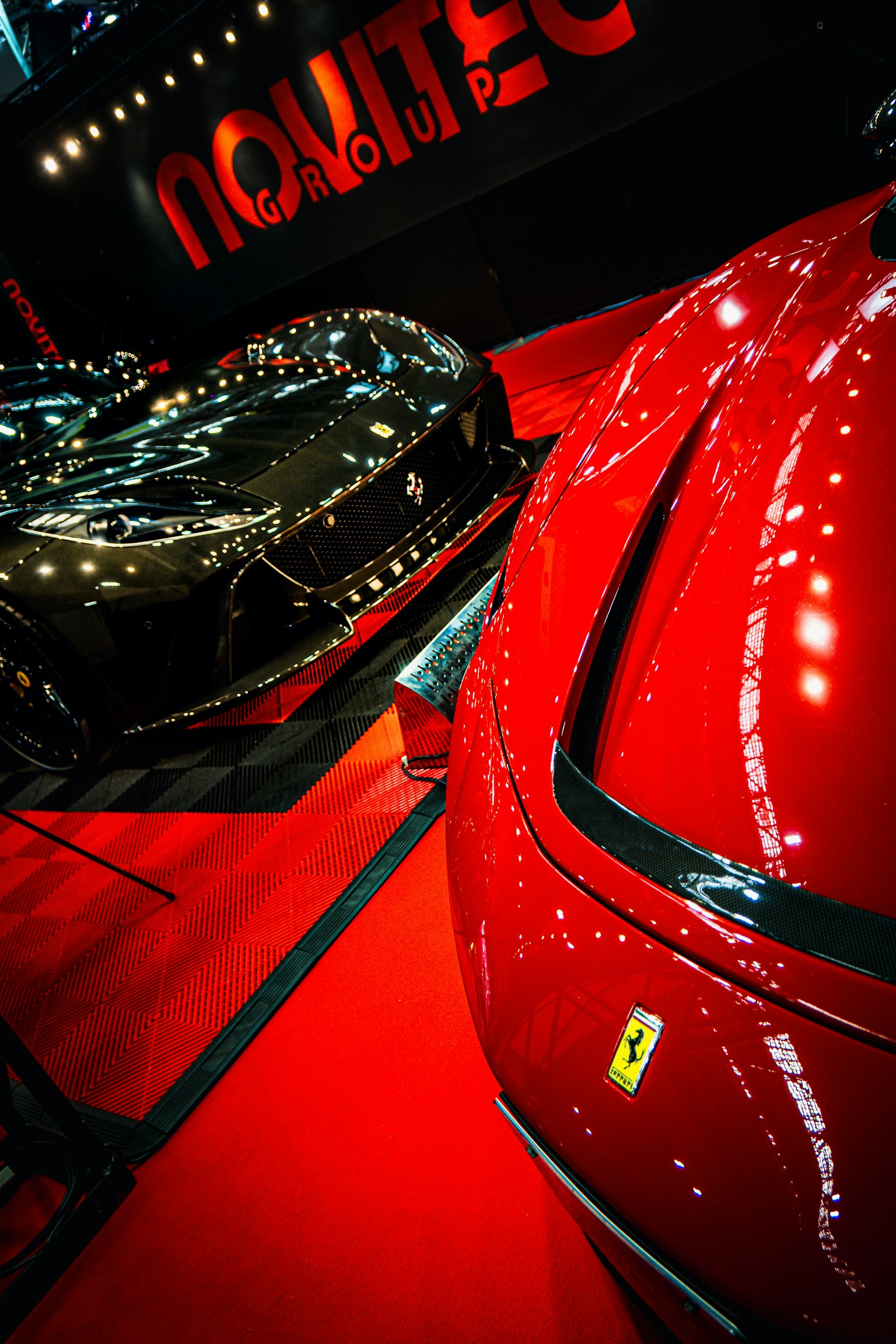 Ferrari đỏ và xe đen được trưng bày tại triển lãm ô tô