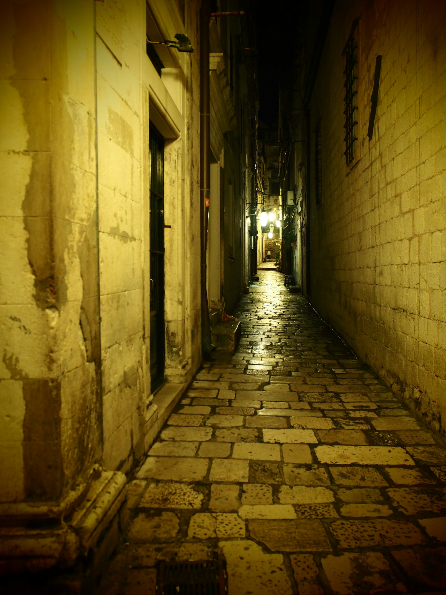 Narrow cobblestone alley illuminated by soft light at night