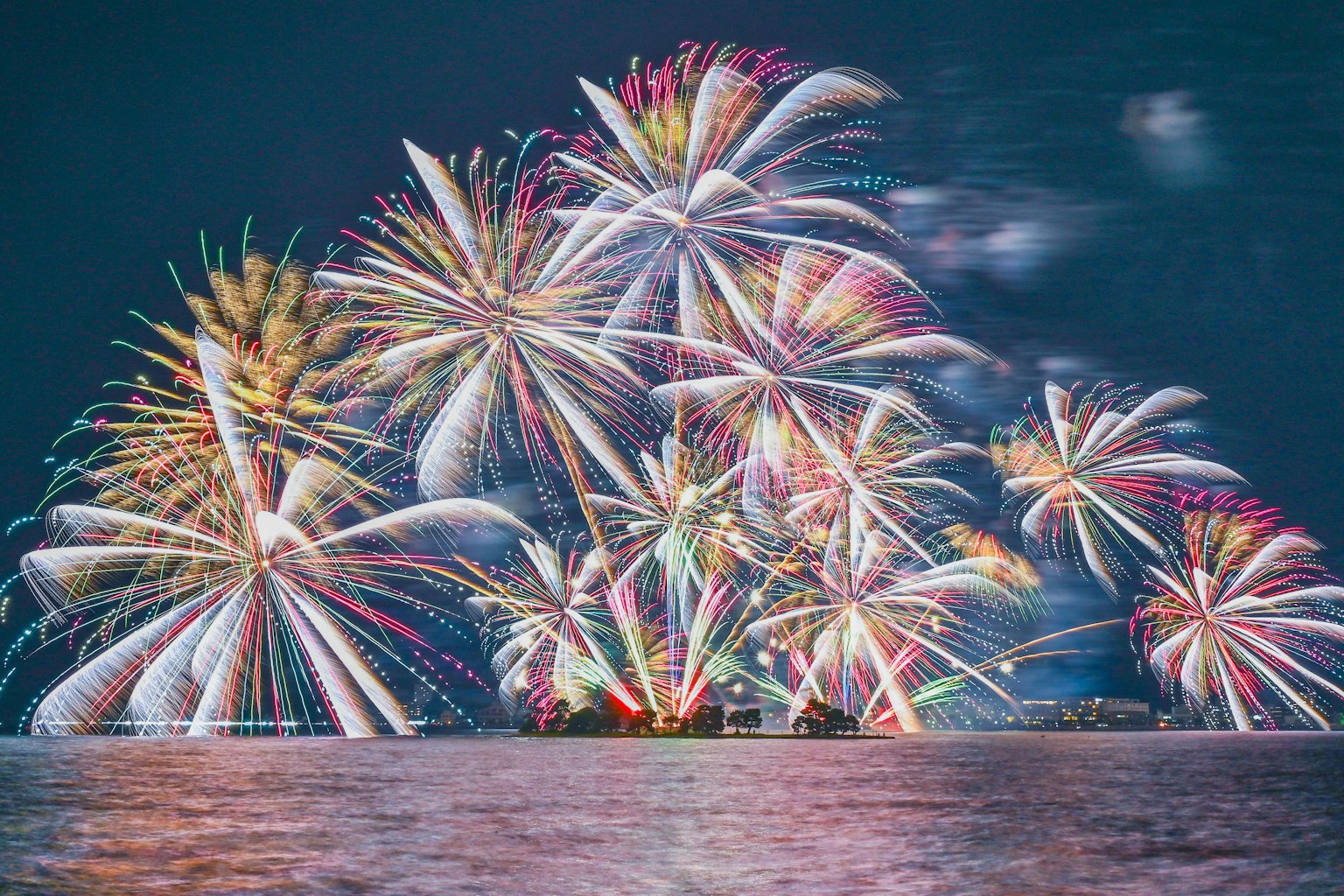 Des feux d'artifice colorés illuminant le ciel nocturne reflétés sur la surface de l'eau